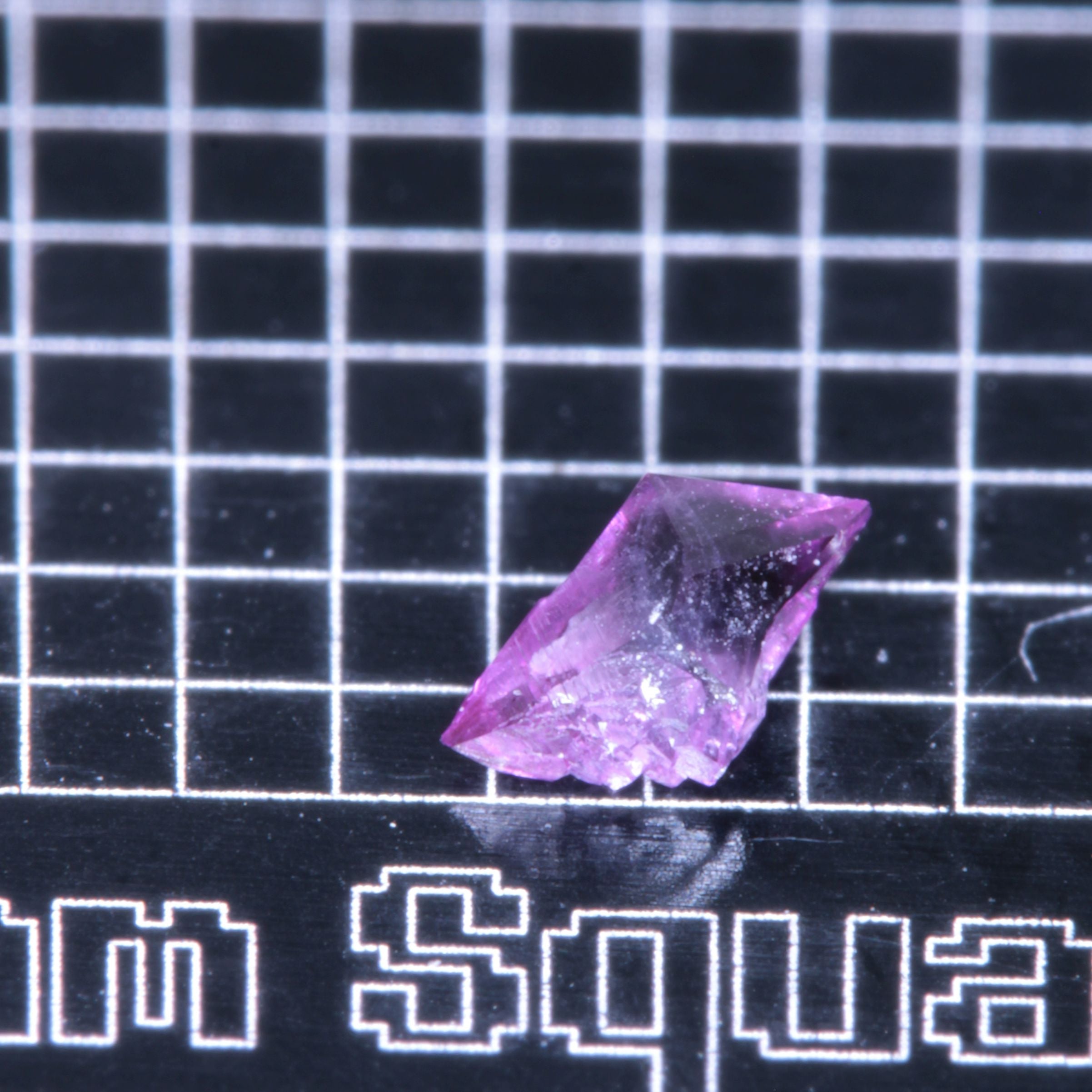 A synthetic ruby crystal on a black grid background