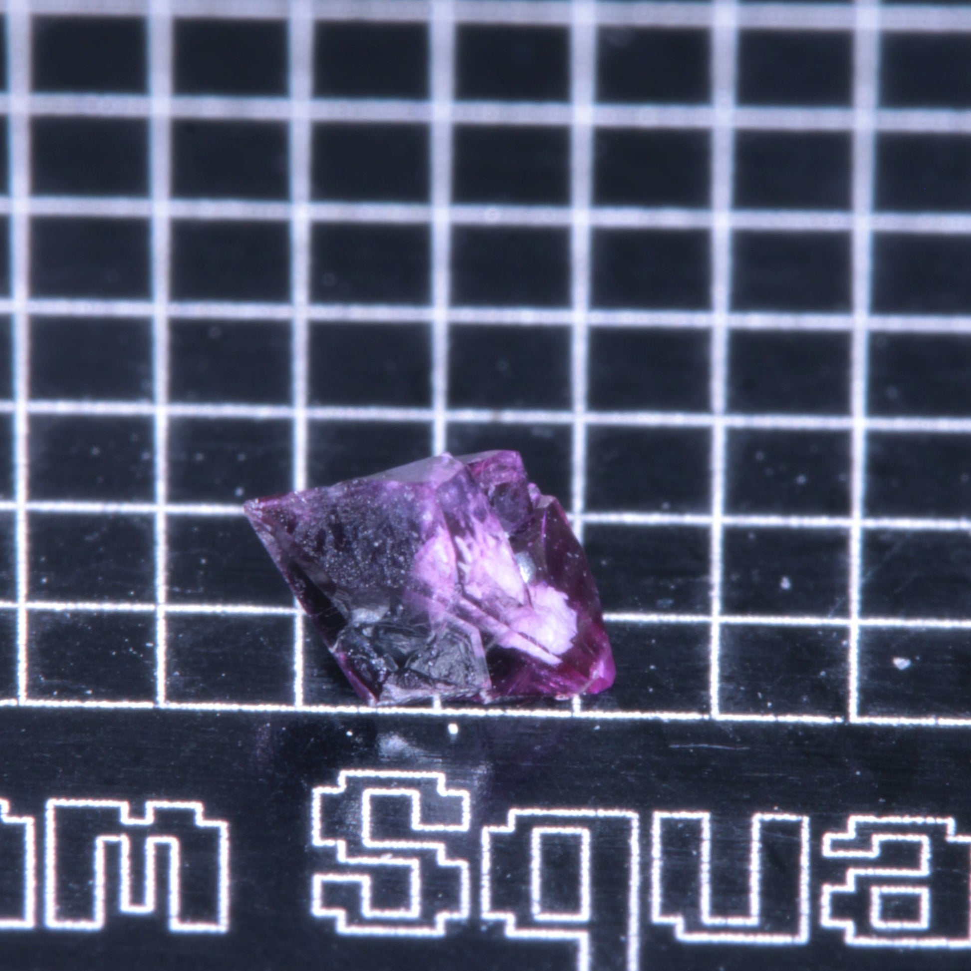 A synthetic ruby crystal on a black grid background