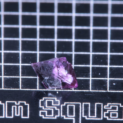 A synthetic ruby crystal on a black grid background