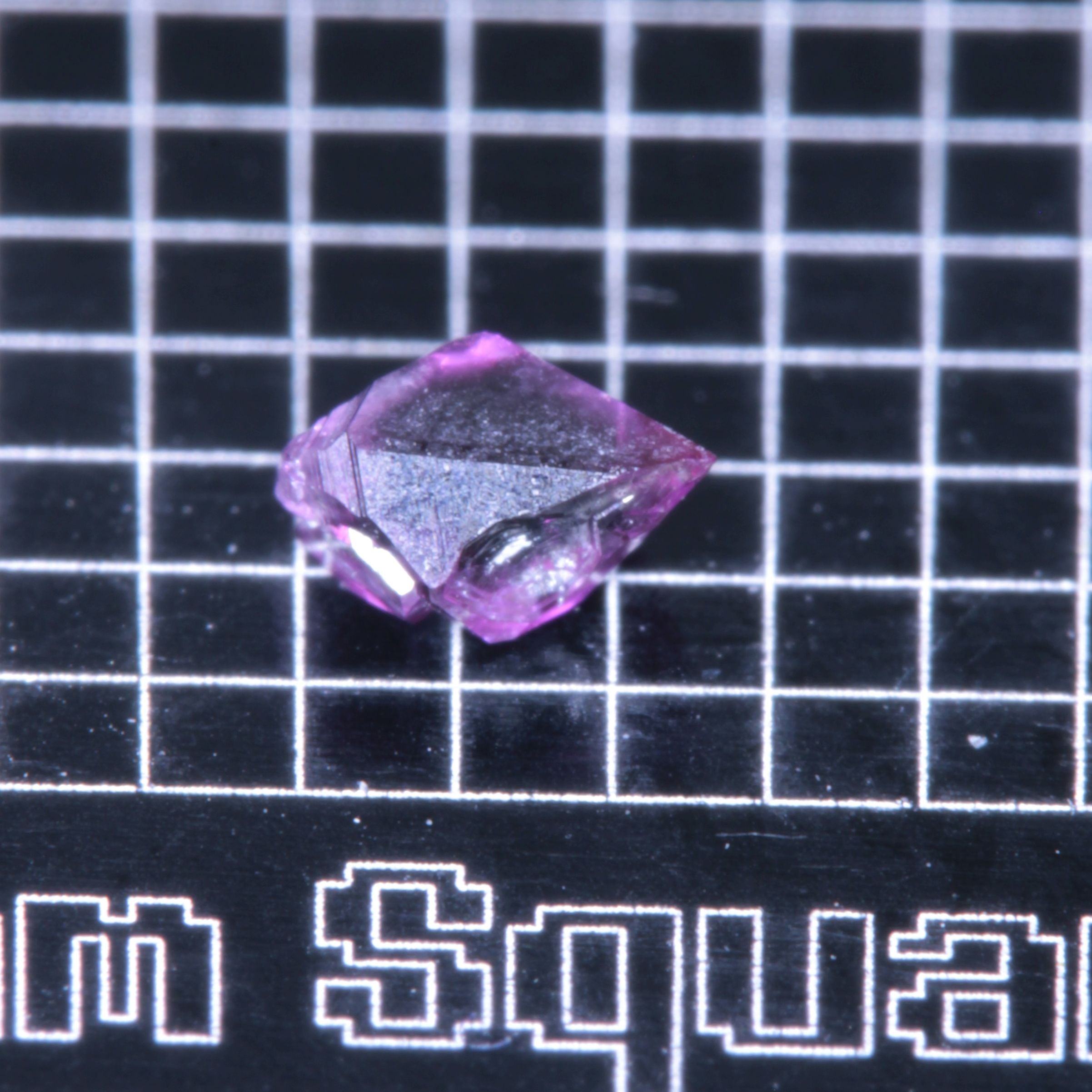 A synthetic ruby crystal on a black grid background