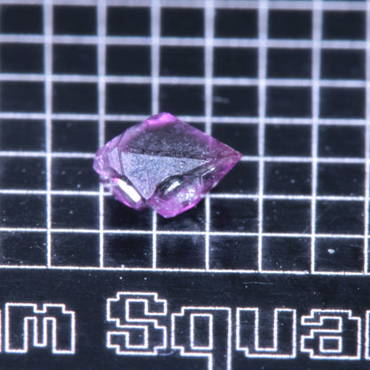 A synthetic ruby crystal on a black grid background