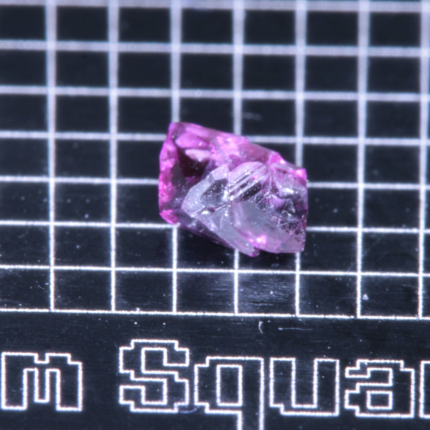A synthetic ruby crystal on a black grid background
