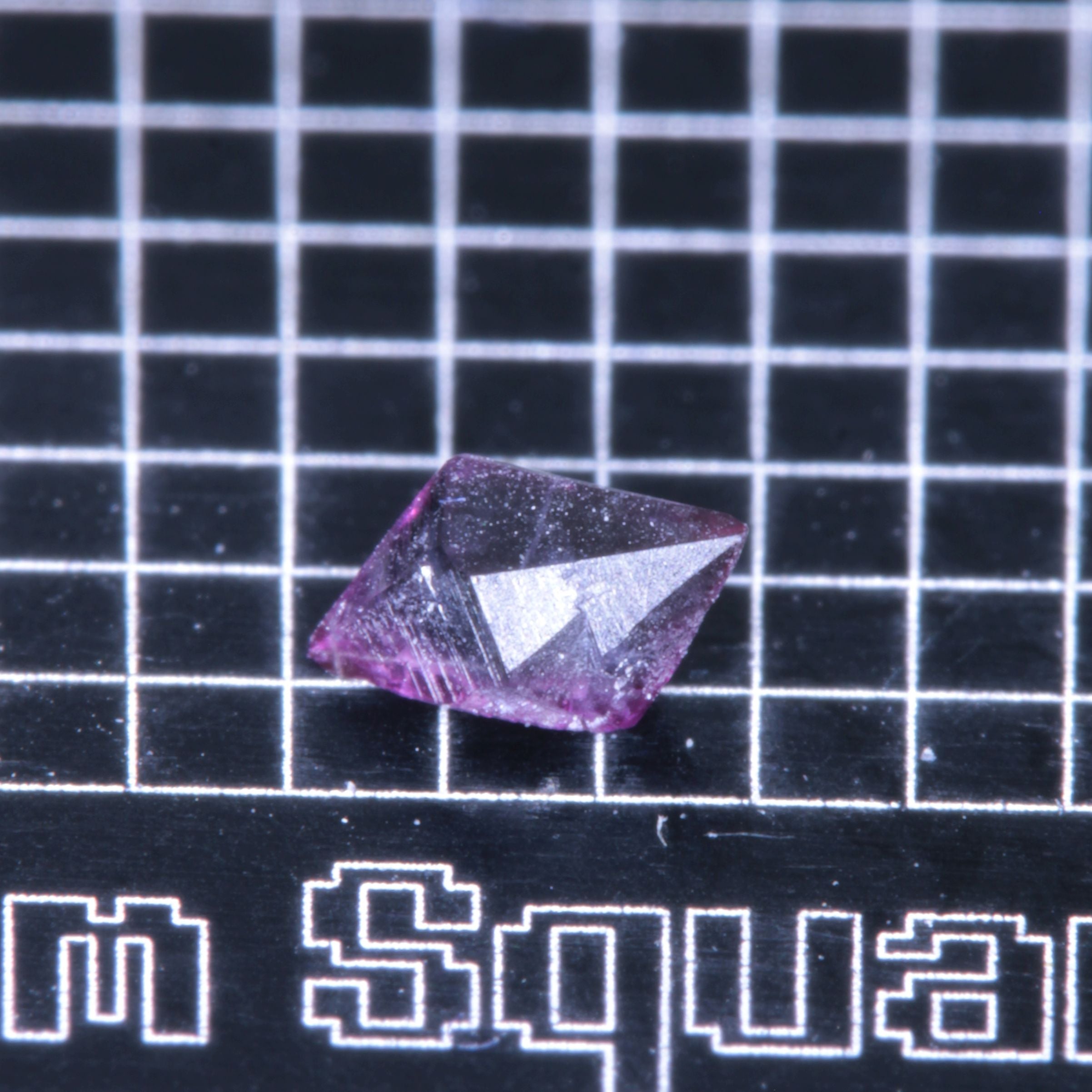 A synthetic ruby crystal on a black grid background