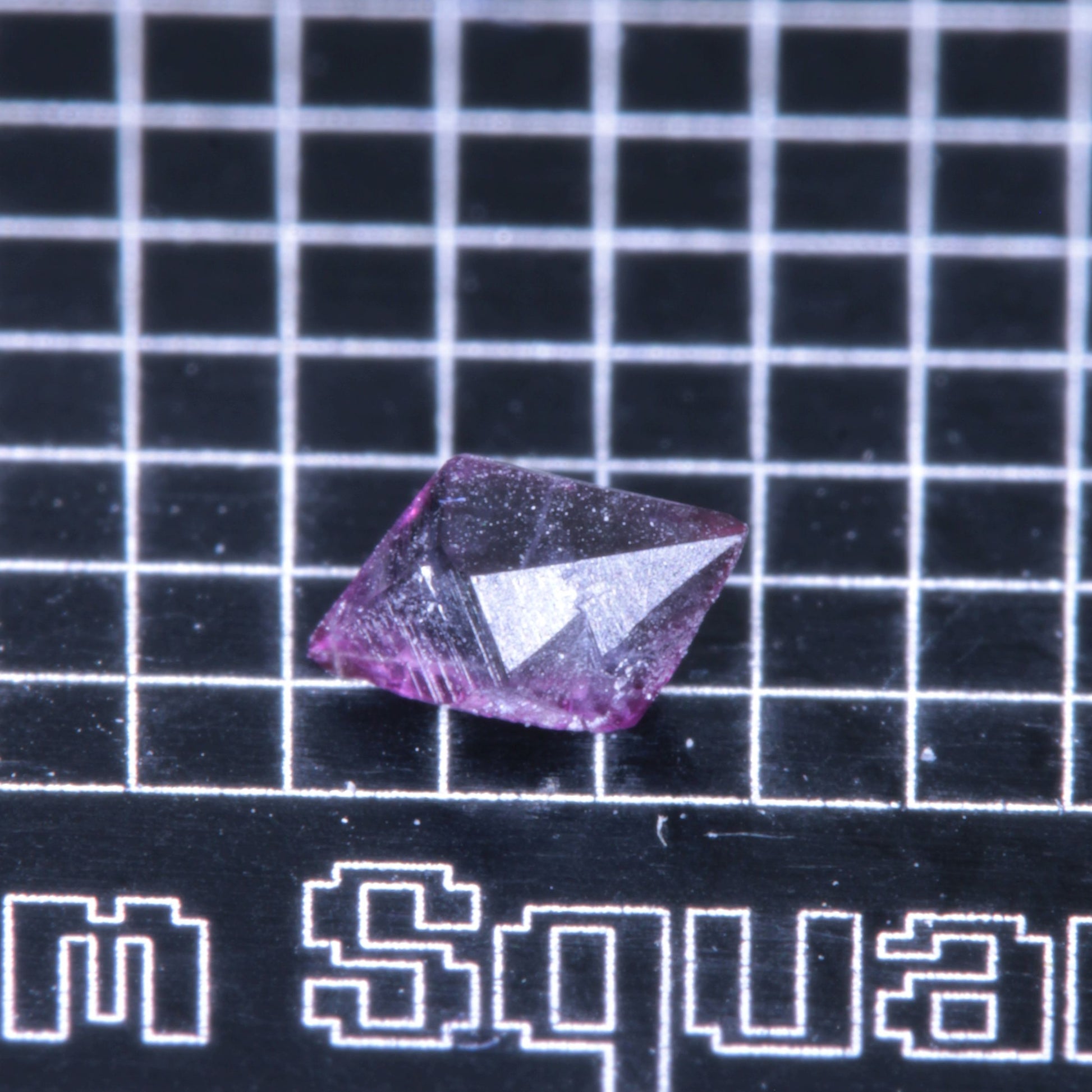 A synthetic ruby crystal on a black grid background