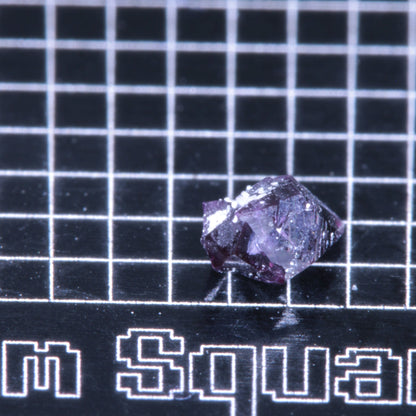 A synthetic ruby crystal on a black grid background