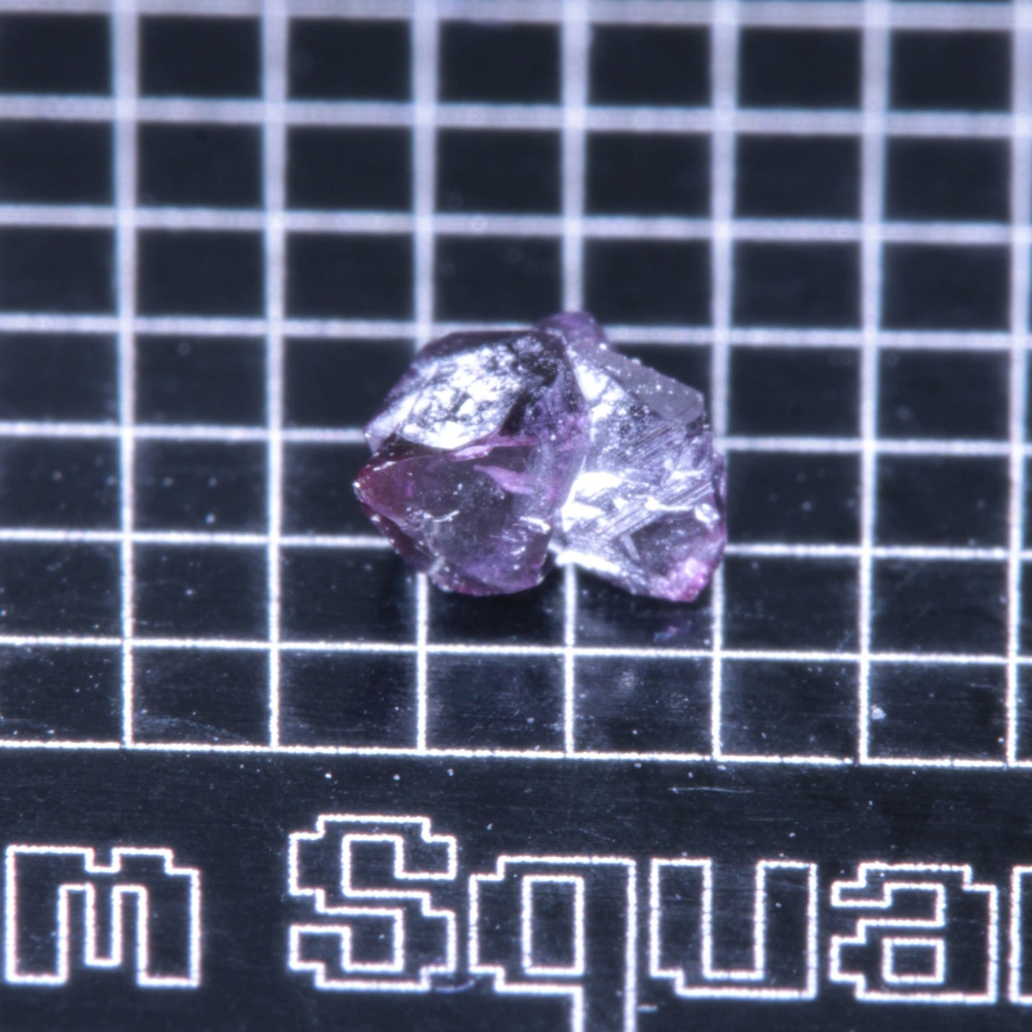 A synthetic ruby crystal on a black grid background
