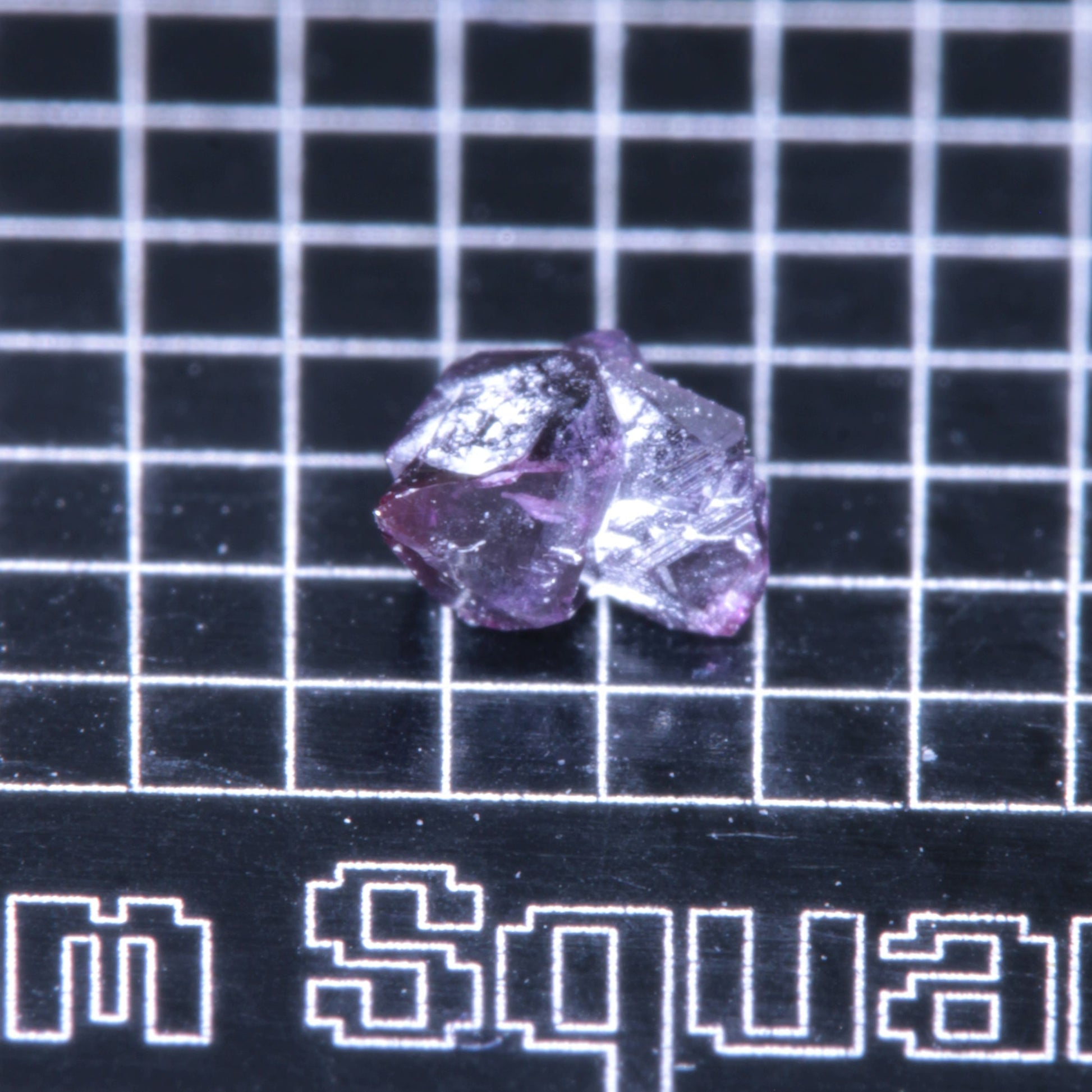 A synthetic ruby crystal on a black grid background