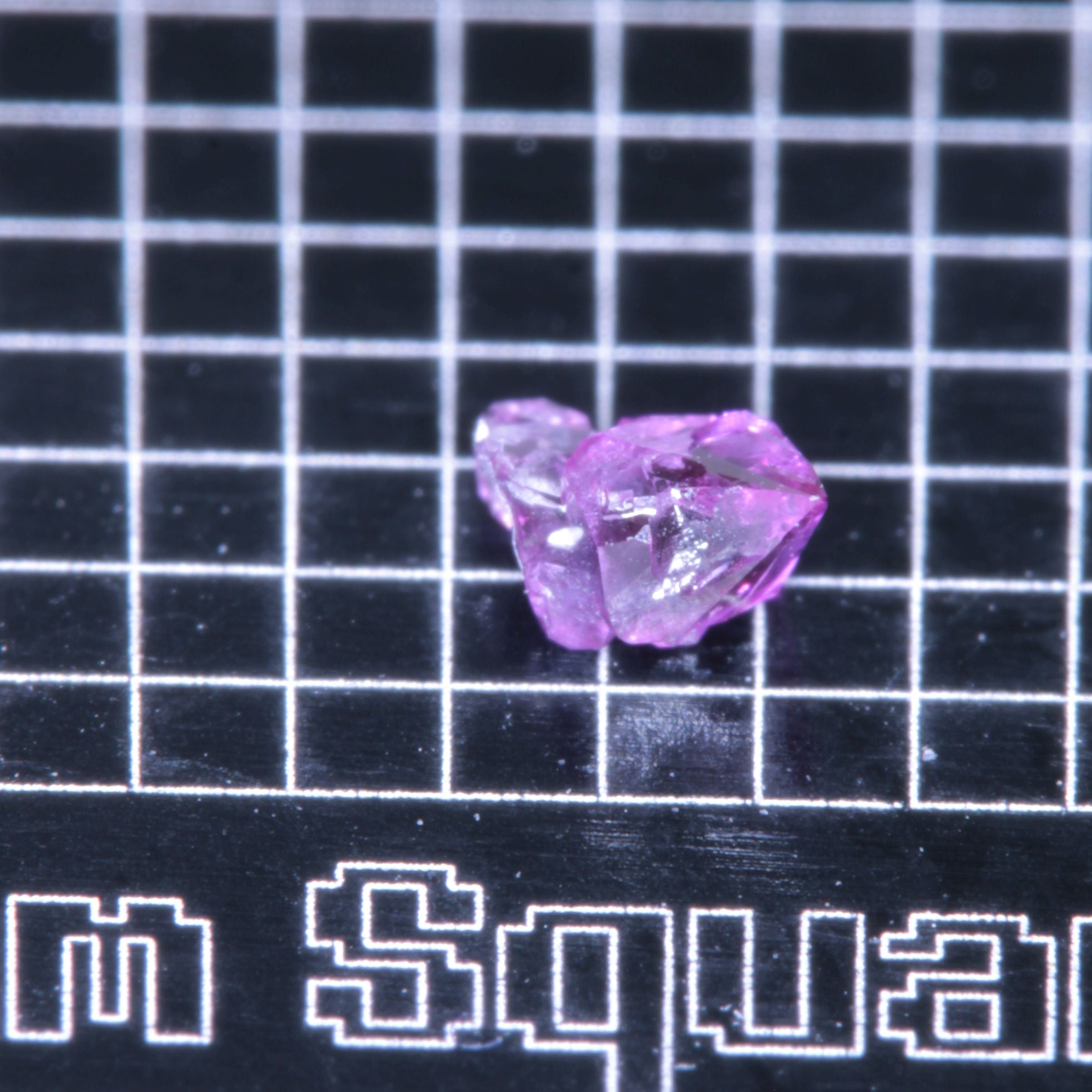A synthetic ruby crystal on a black grid background
