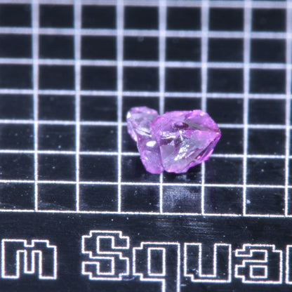 A synthetic ruby crystal on a black grid background