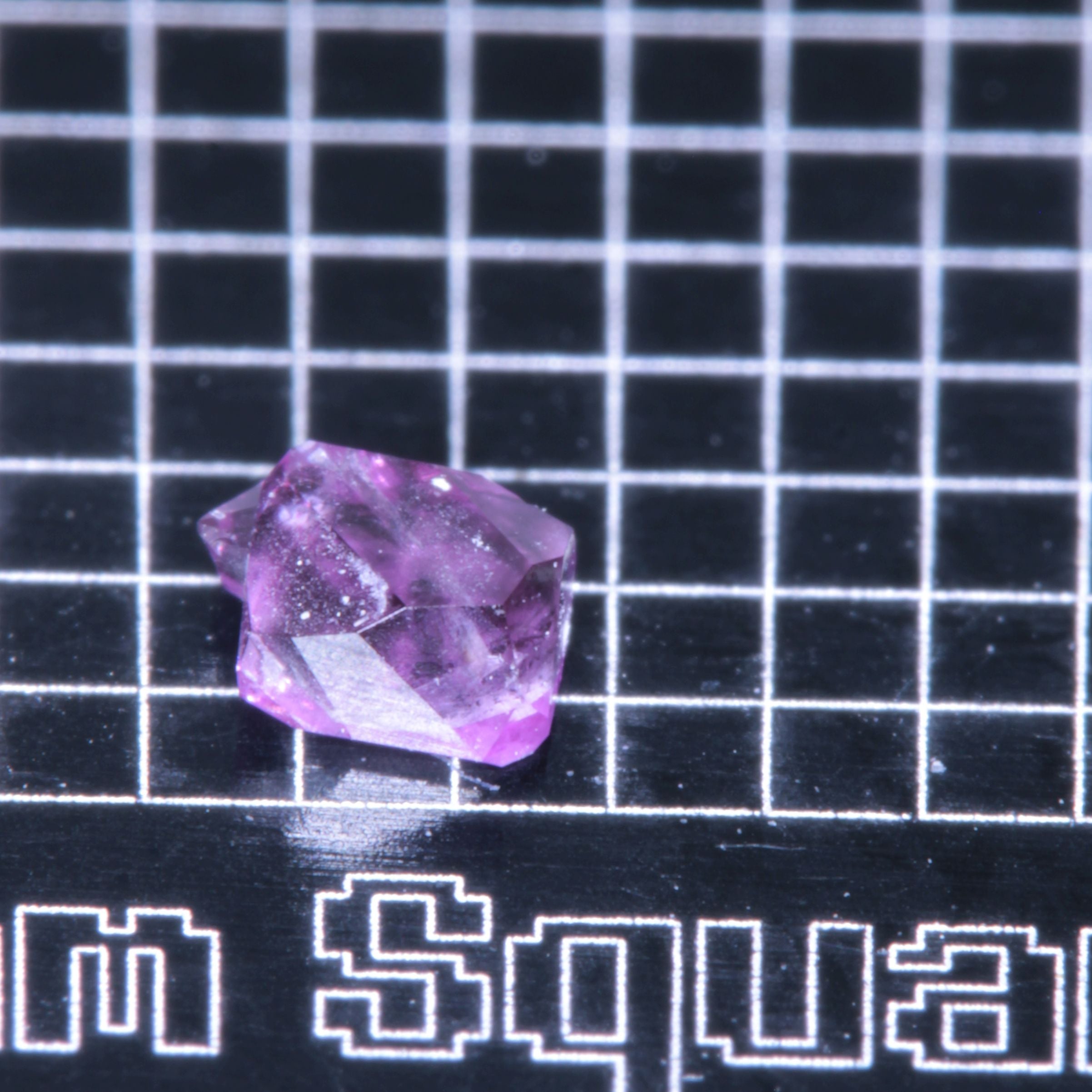 A synthetic ruby crystal on a black grid background