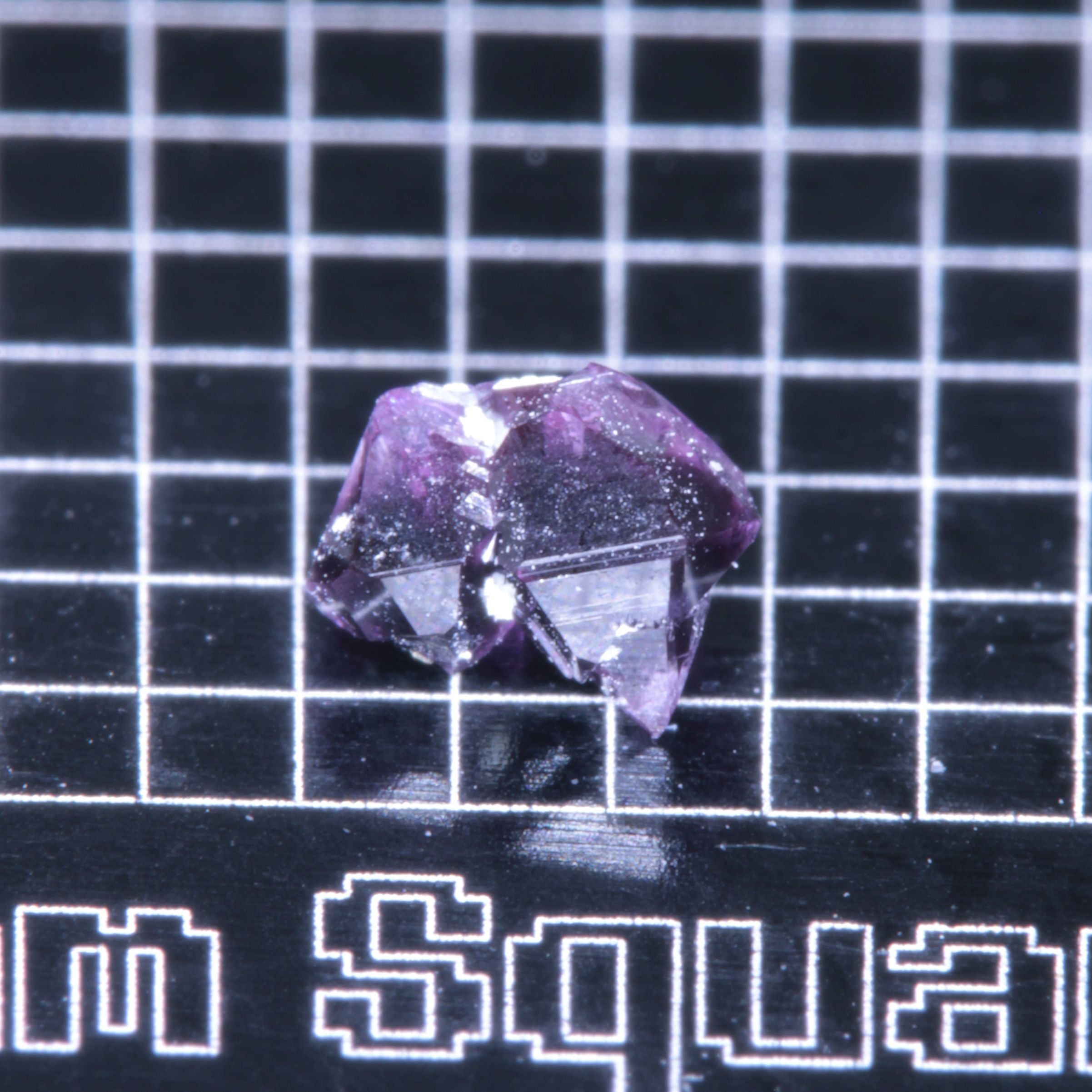 A synthetic ruby crystal on a black grid background