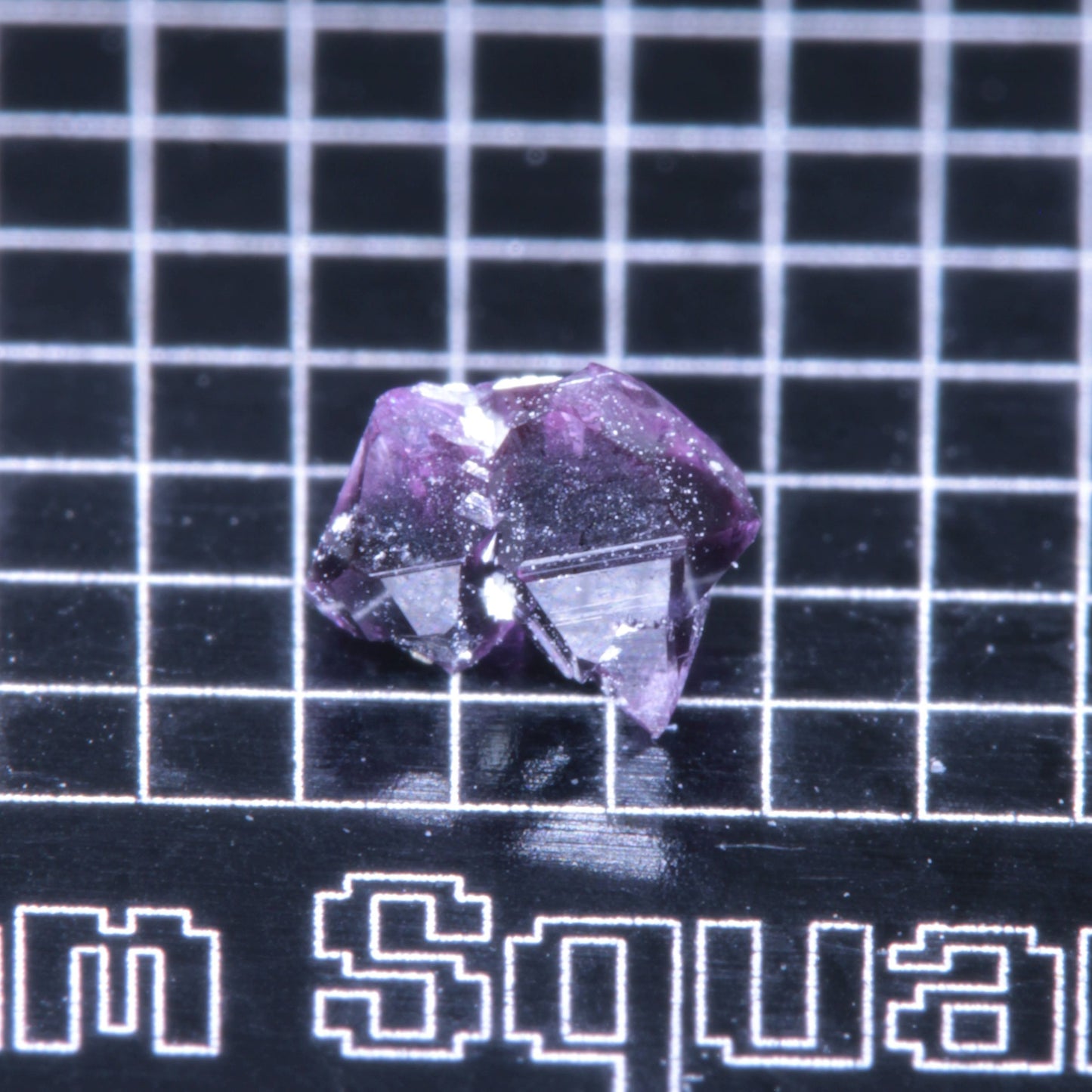A synthetic ruby crystal on a black grid background