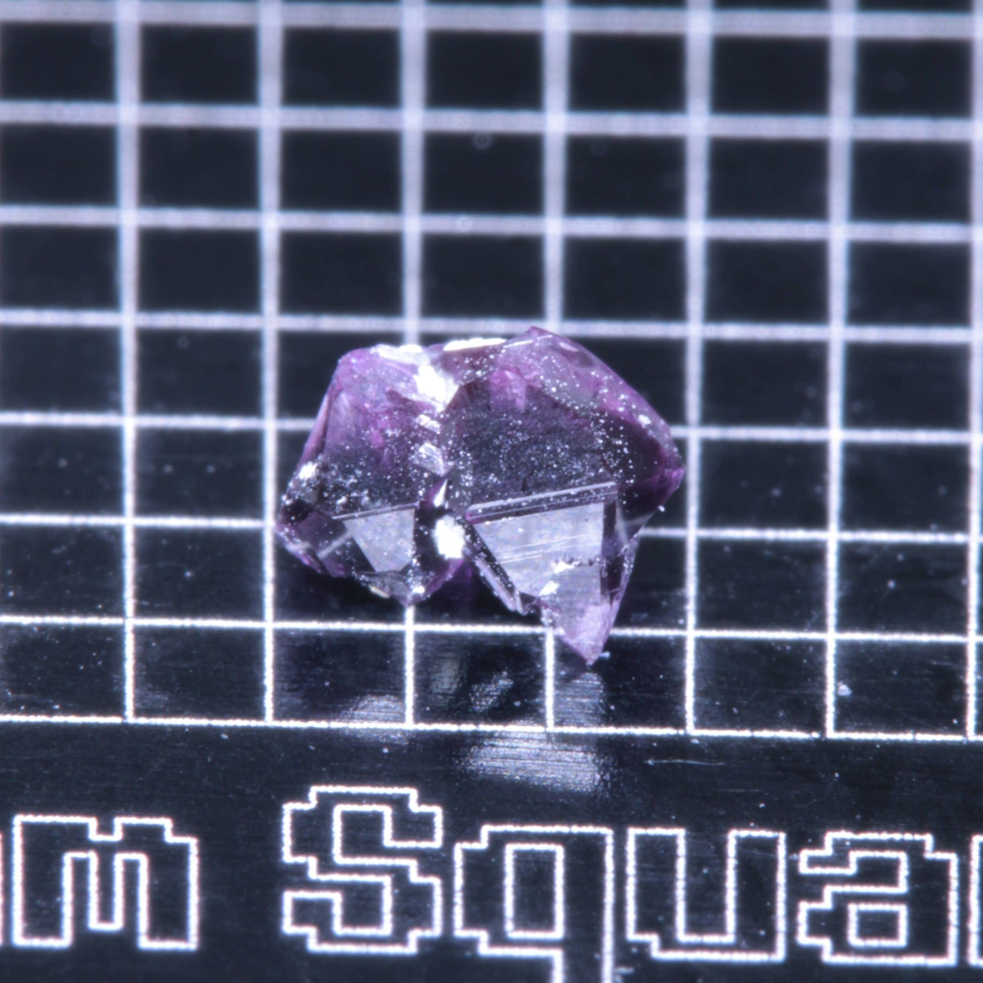 A synthetic ruby crystal on a black grid background