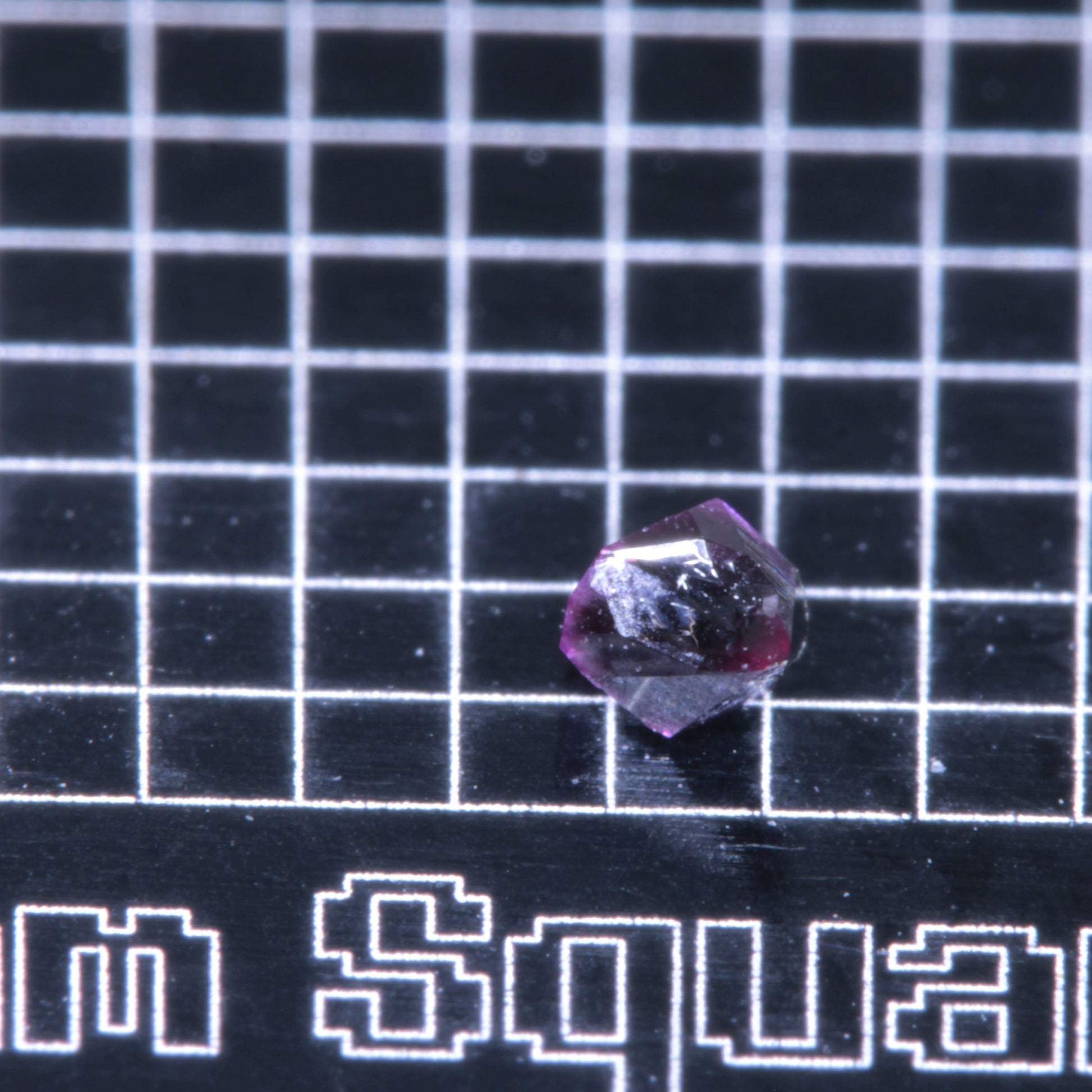 A synthetic ruby crystal on a black grid background