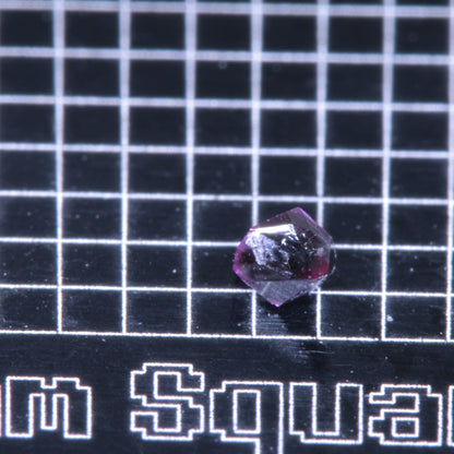 A synthetic ruby crystal on a black grid background