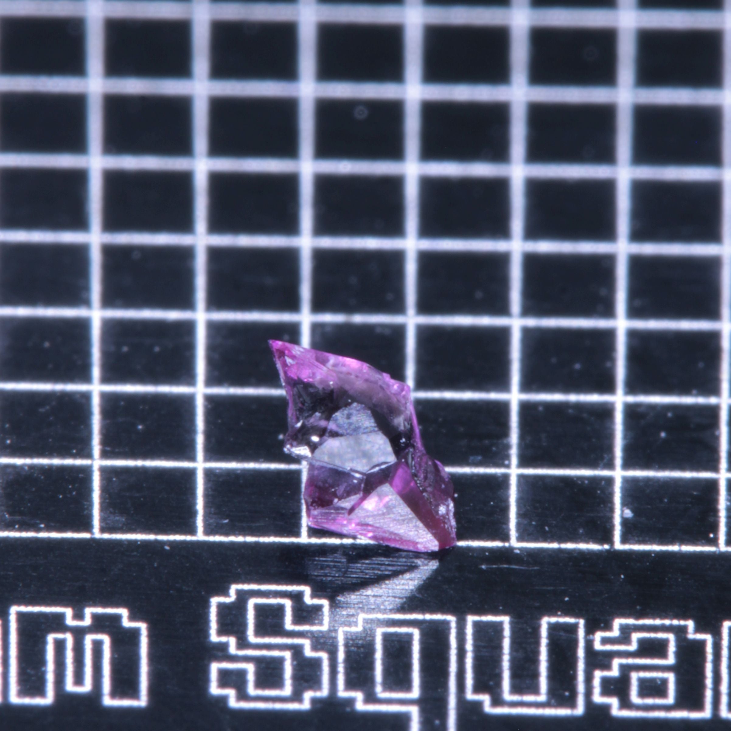 A synthetic ruby crystal on a black grid background