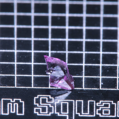 A synthetic ruby crystal on a black grid background