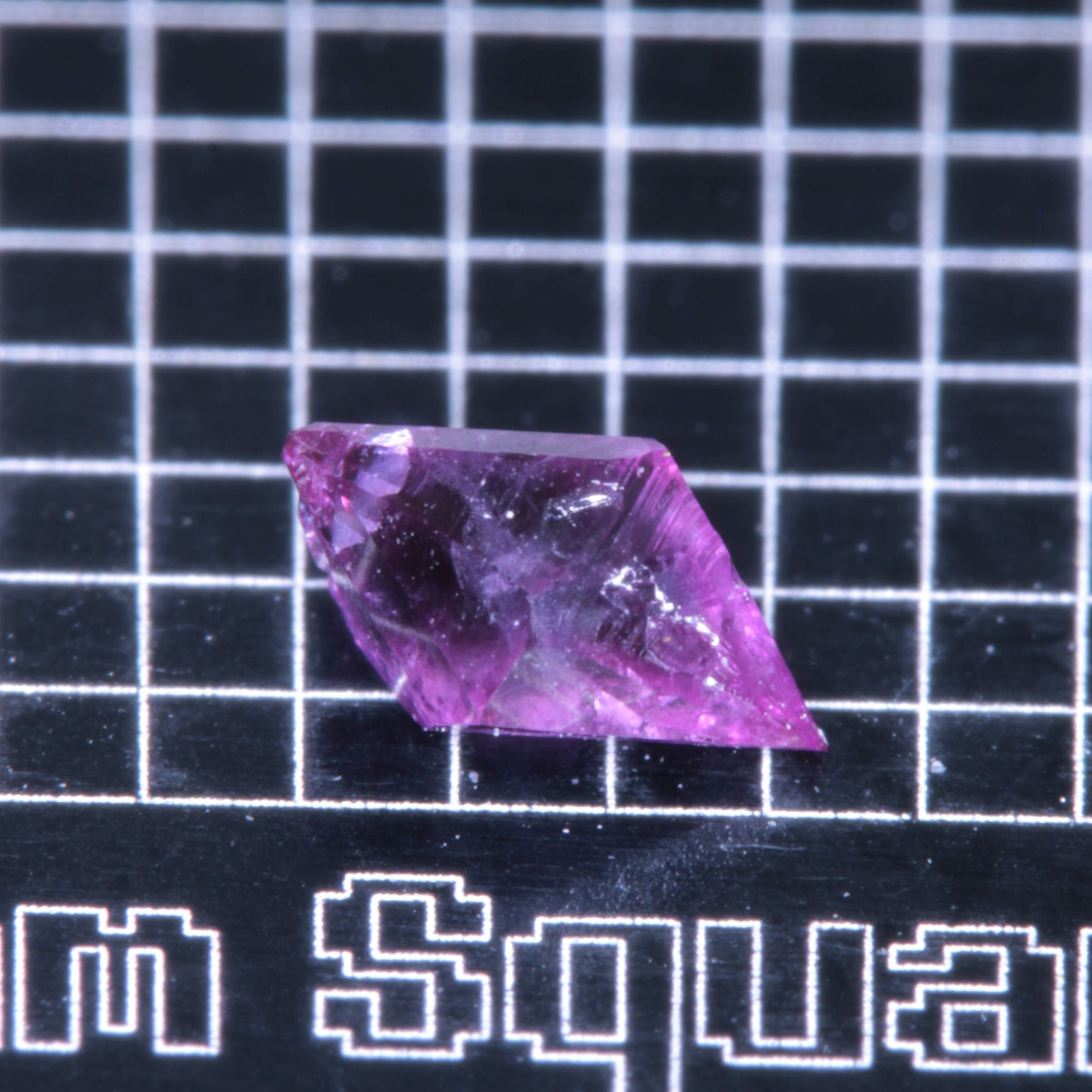 A synthetic ruby crystal on a black grid background
