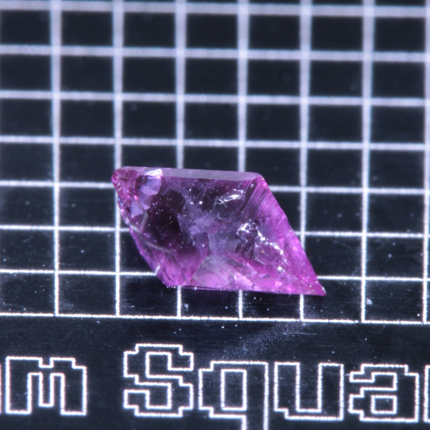 A synthetic ruby crystal on a black grid background