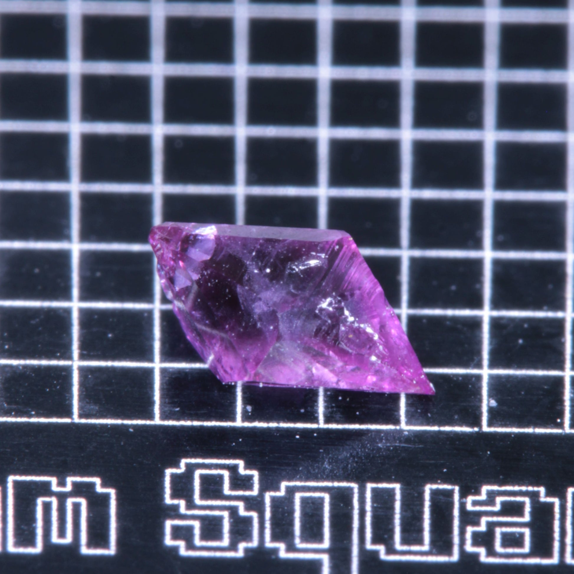 A synthetic ruby crystal on a black grid background