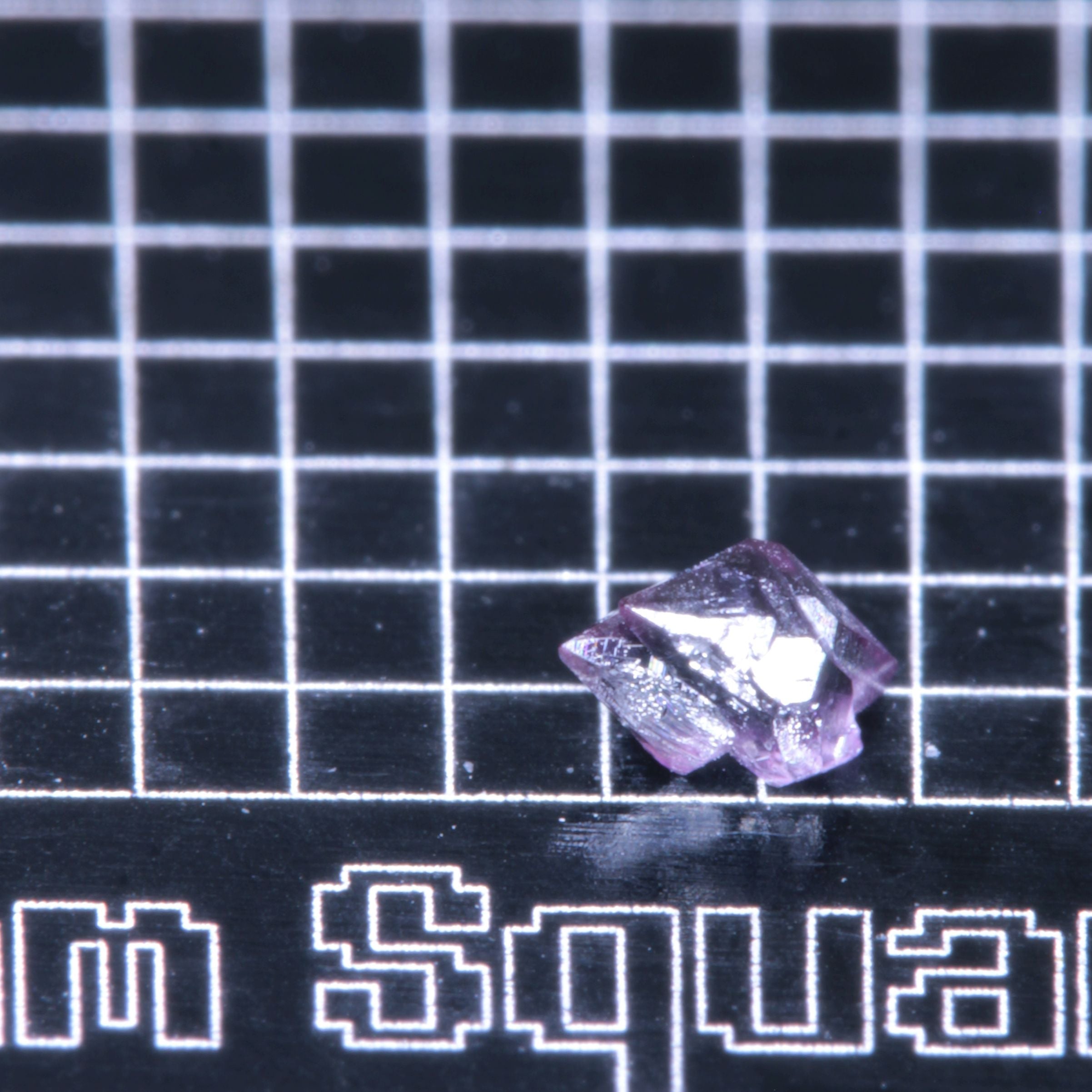 A synthetic ruby crystal on a black grid background