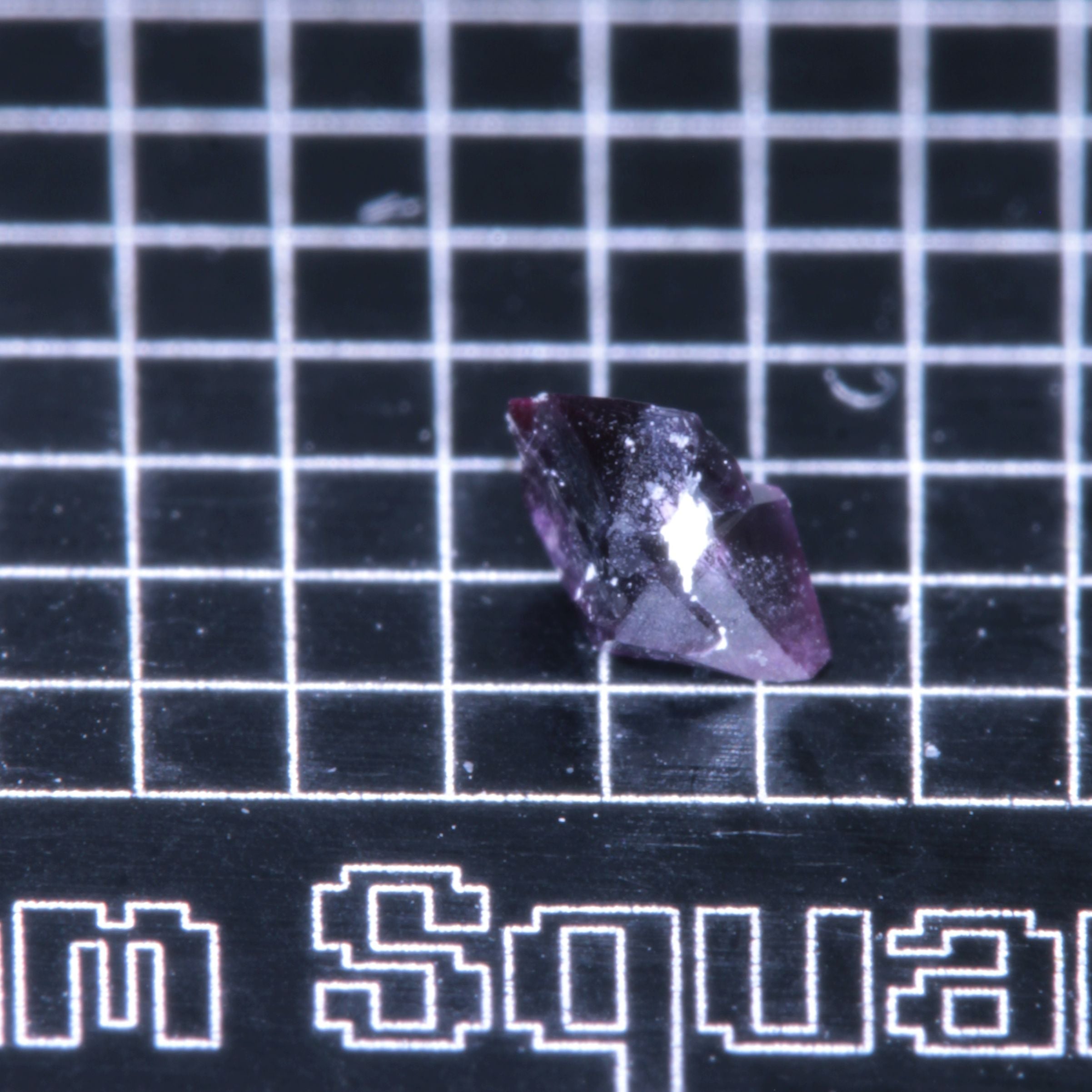 A synthetic ruby crystal on a black grid background