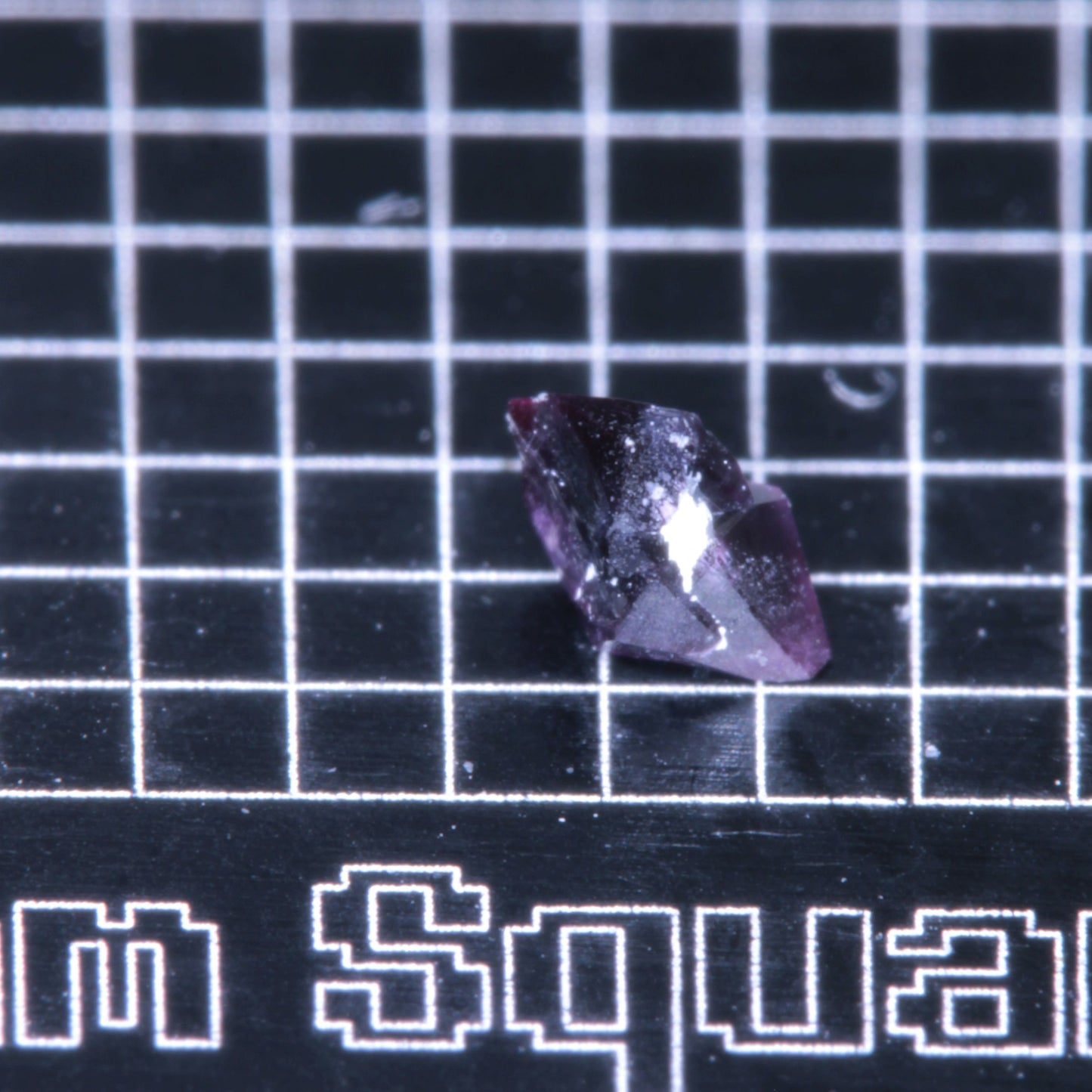 A synthetic ruby crystal on a black grid background