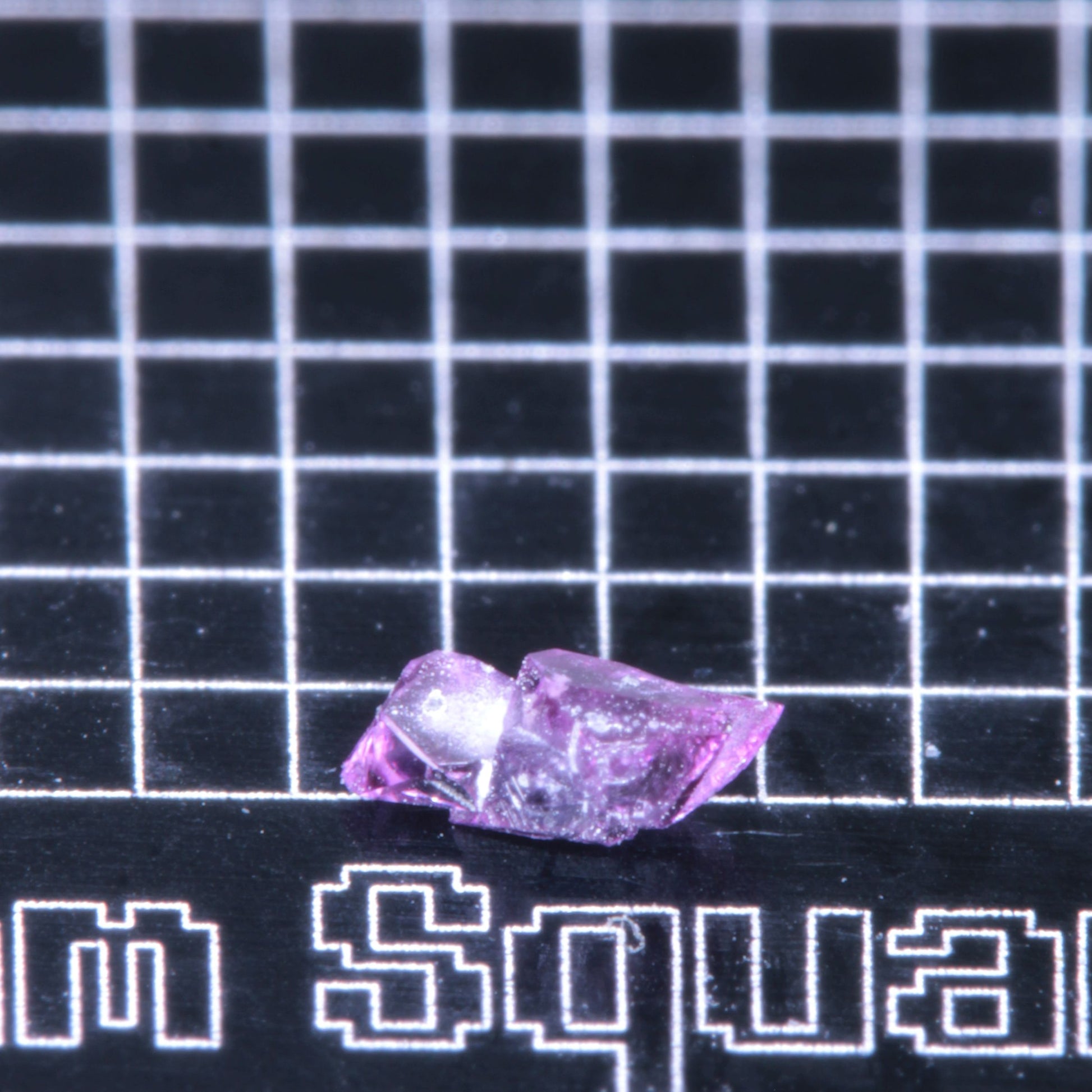 A synthetic ruby crystal on a black grid background