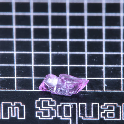 A synthetic ruby crystal on a black grid background
