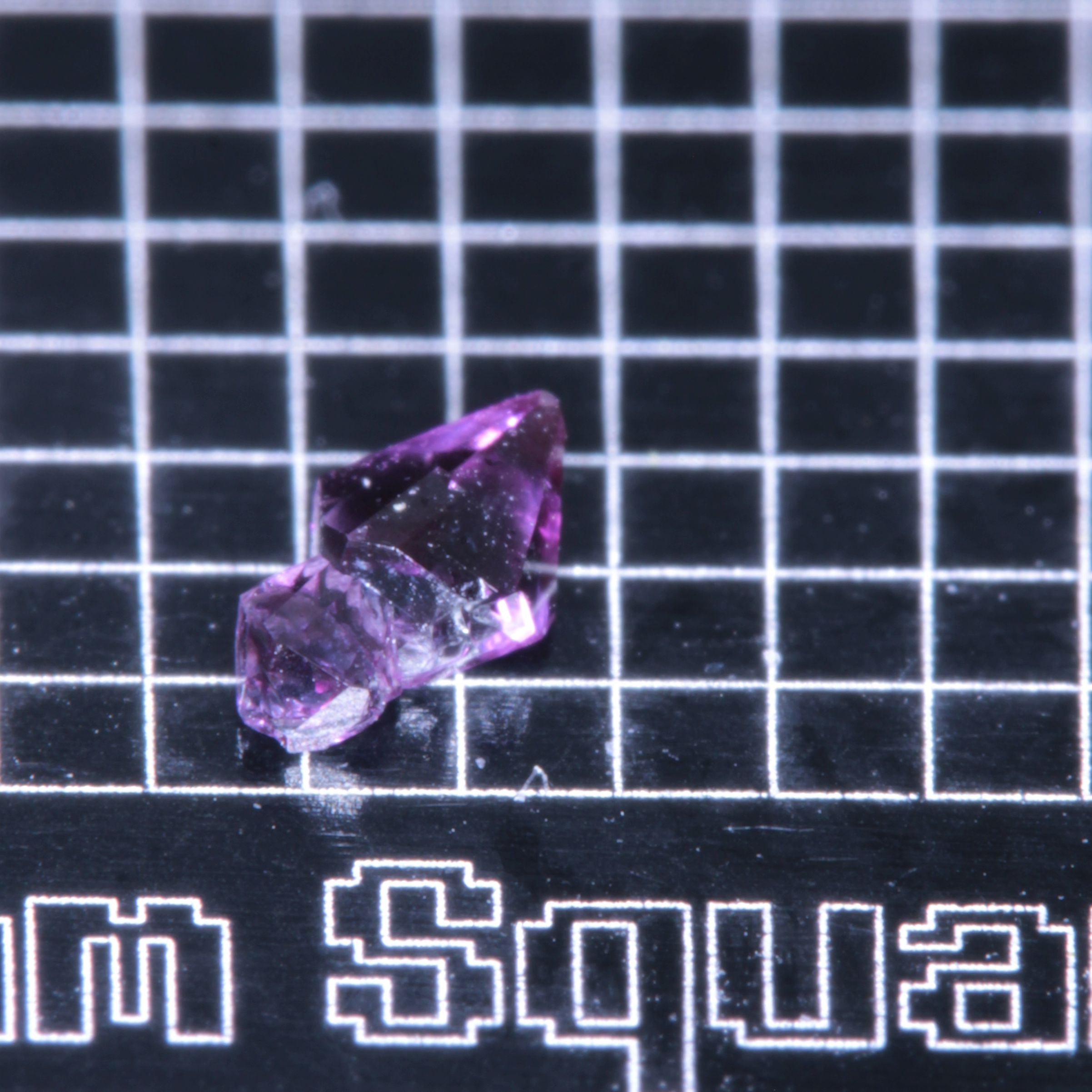 A synthetic ruby crystal on a black grid background