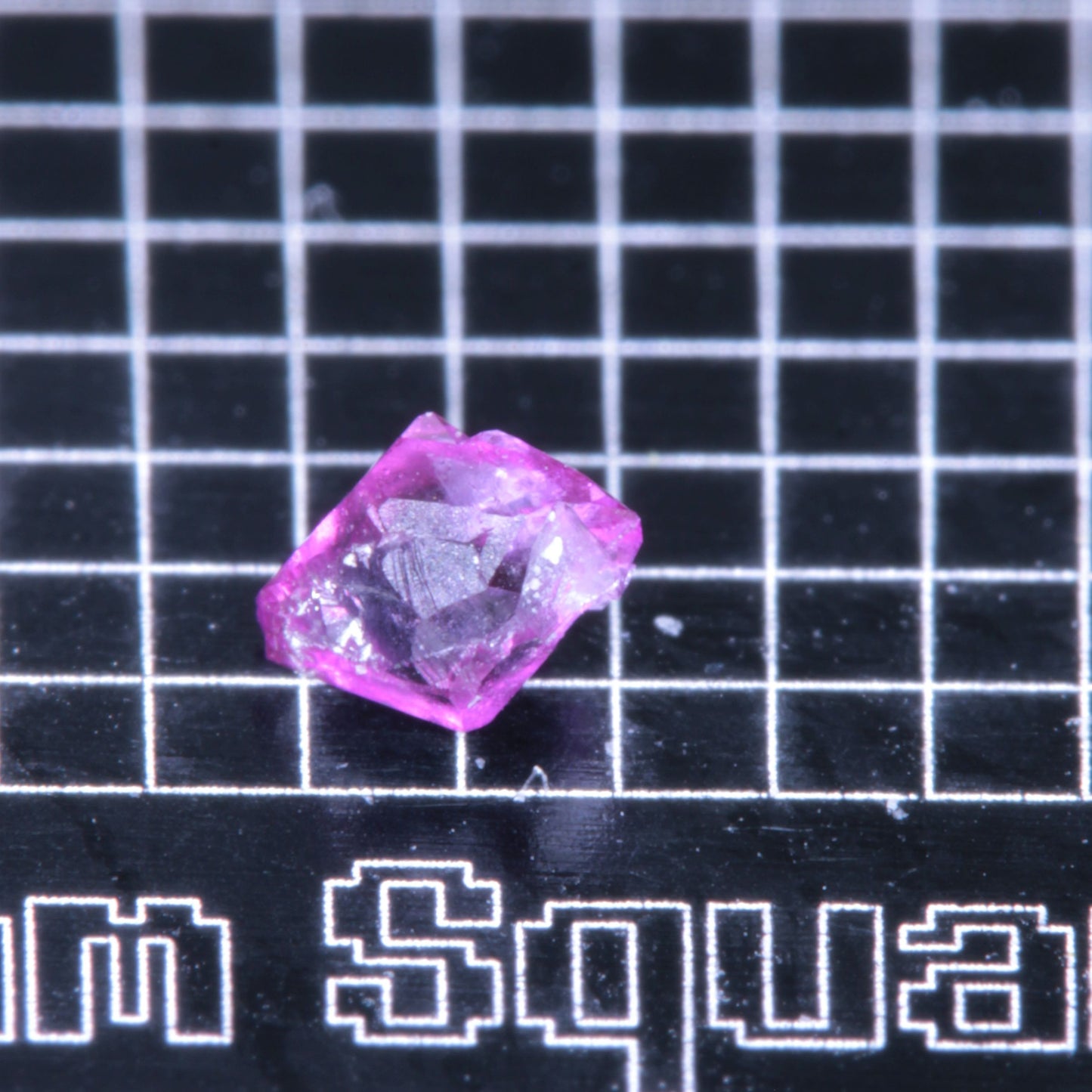A synthetic ruby crystal on a black grid background