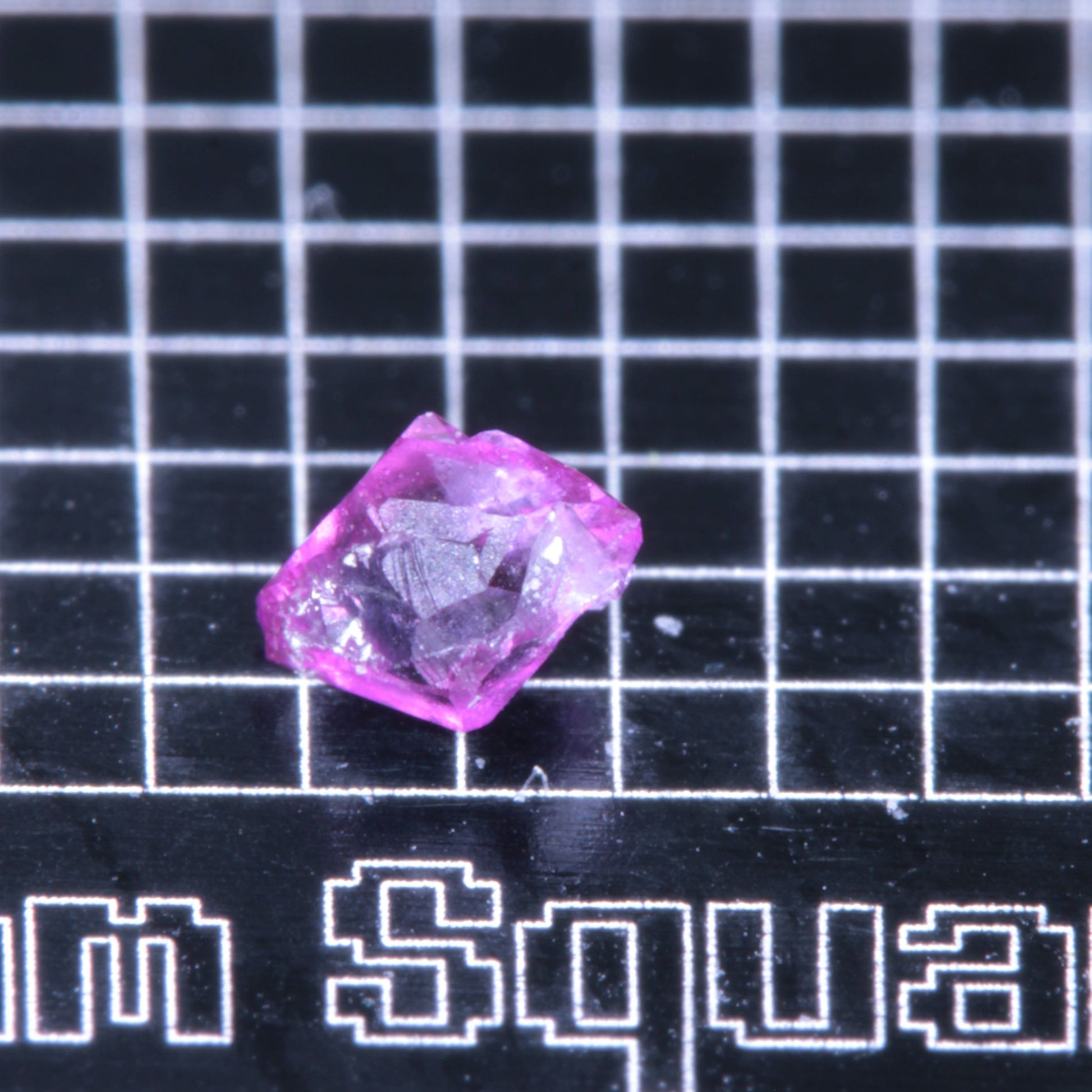 A synthetic ruby crystal on a black grid background