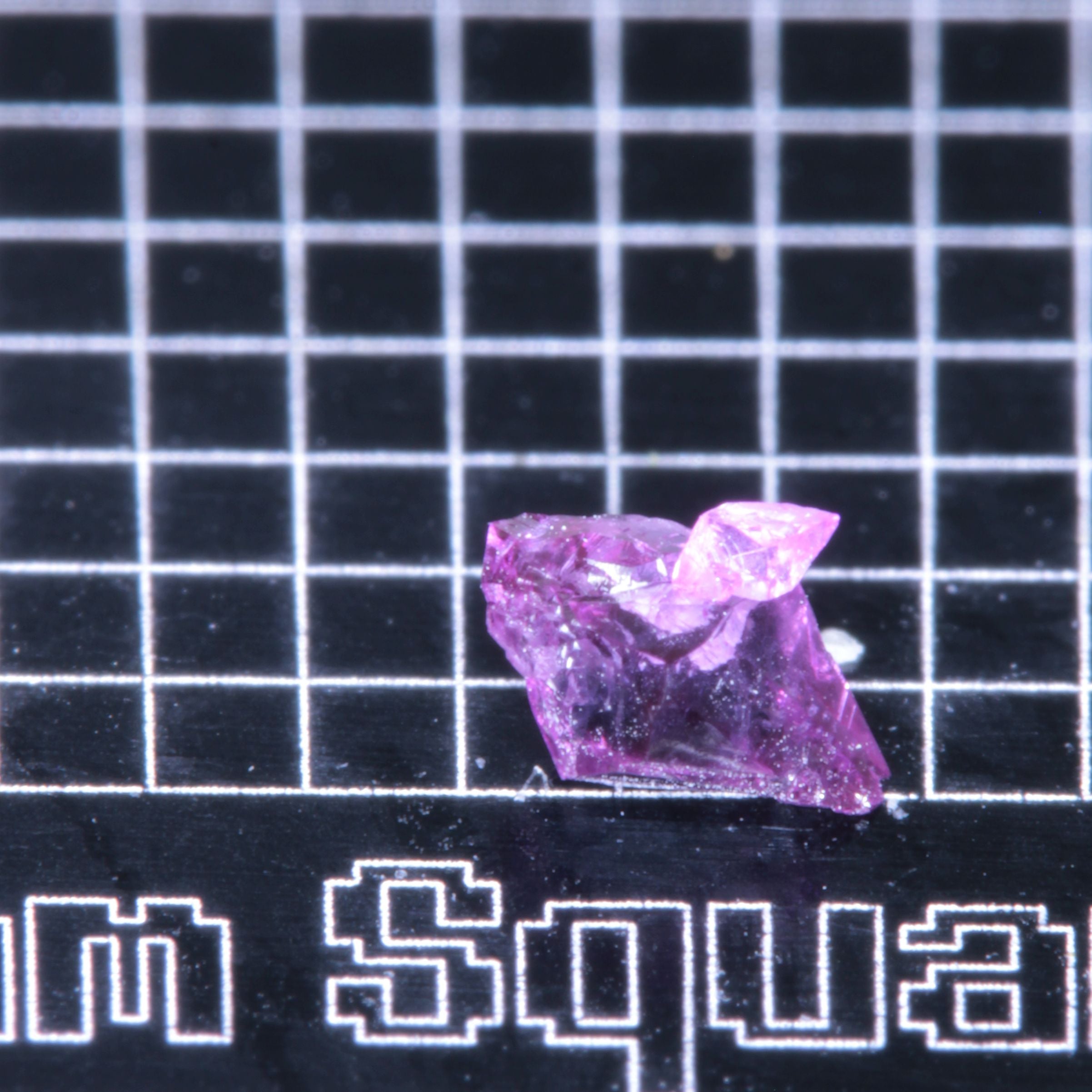 A synthetic ruby crystal on a black grid background