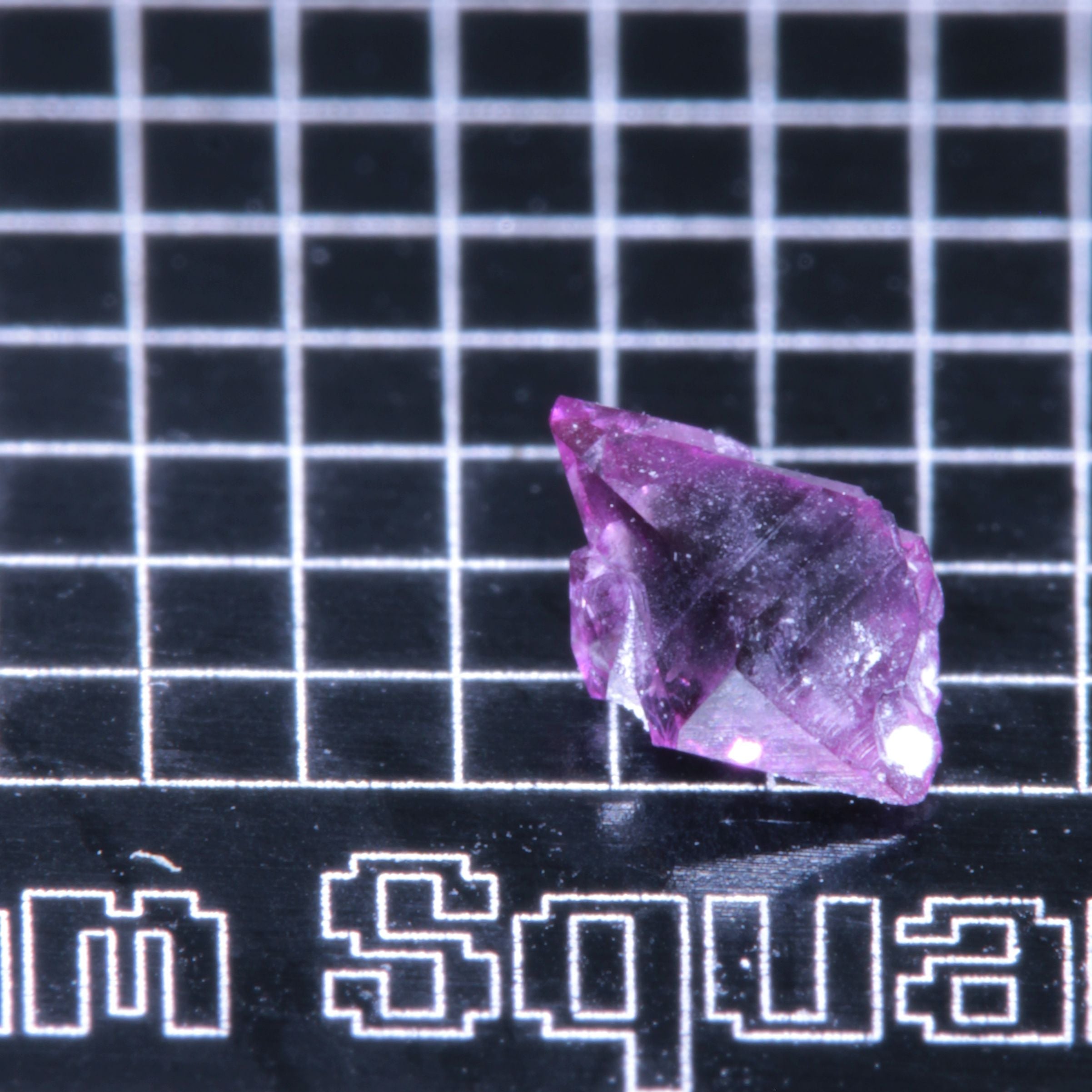 A synthetic ruby crystal on a black grid background