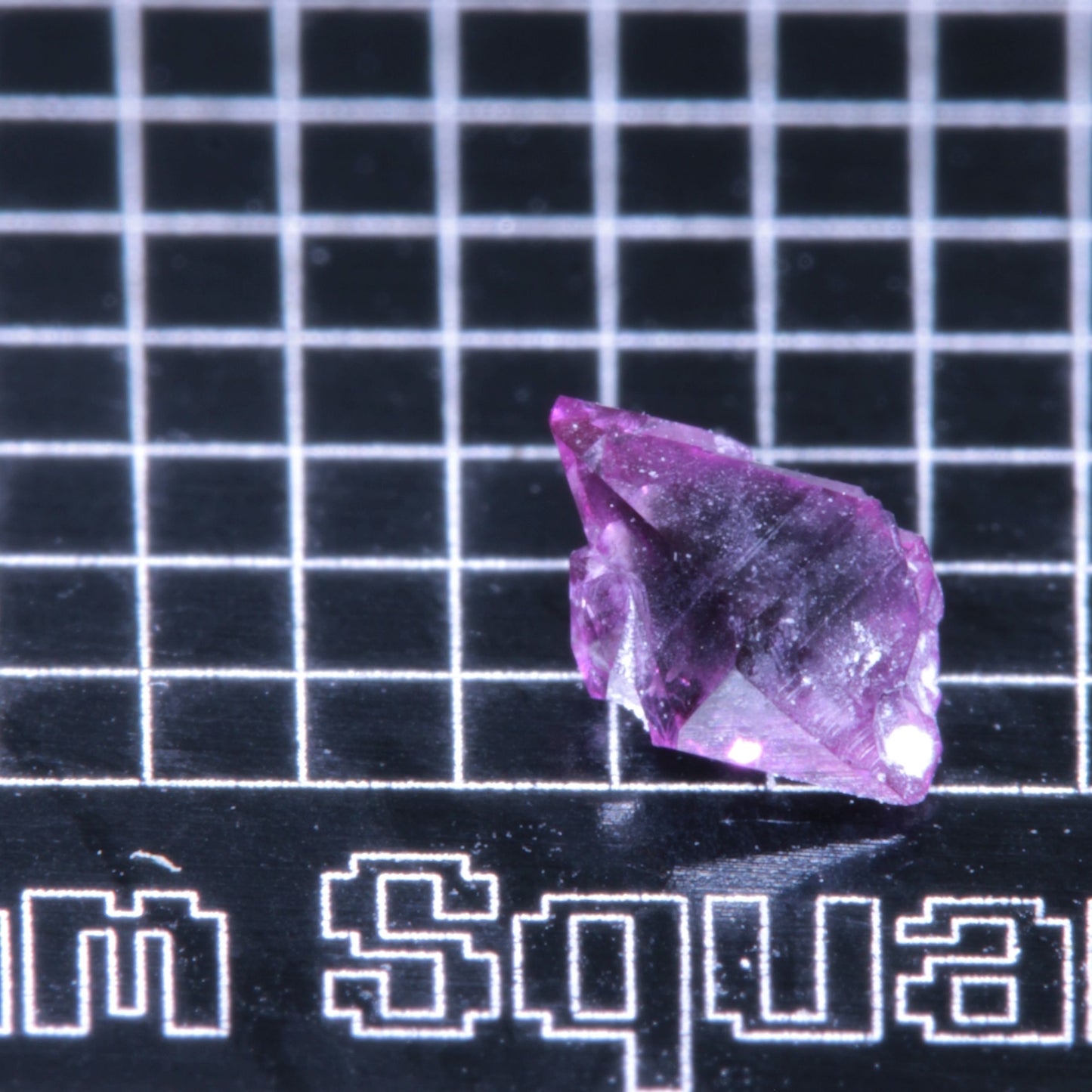 A synthetic ruby crystal on a black grid background