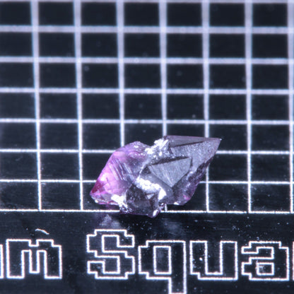A synthetic ruby crystal on a black grid background