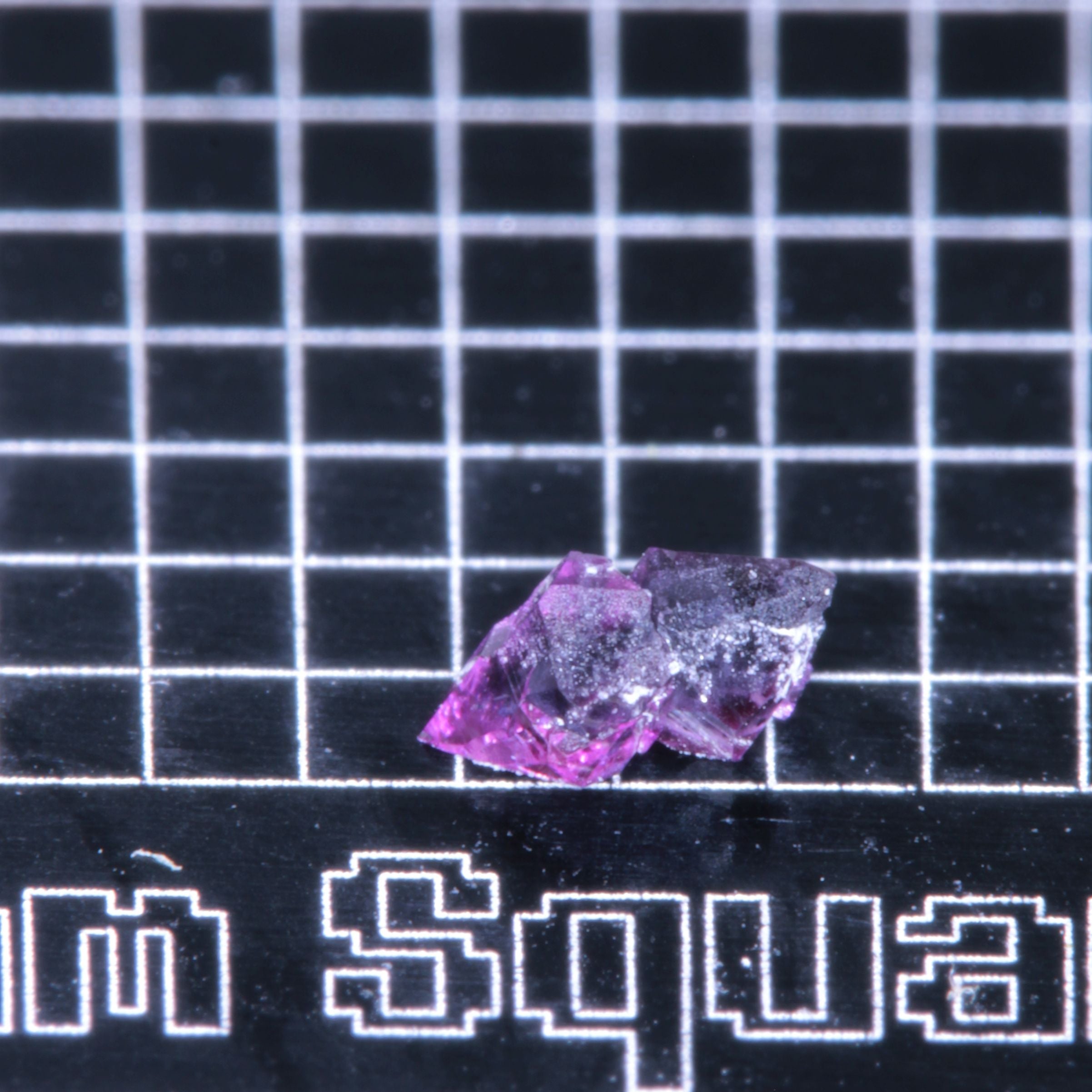 A synthetic ruby crystal on a black grid background