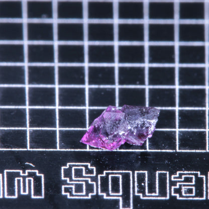 A synthetic ruby crystal on a black grid background
