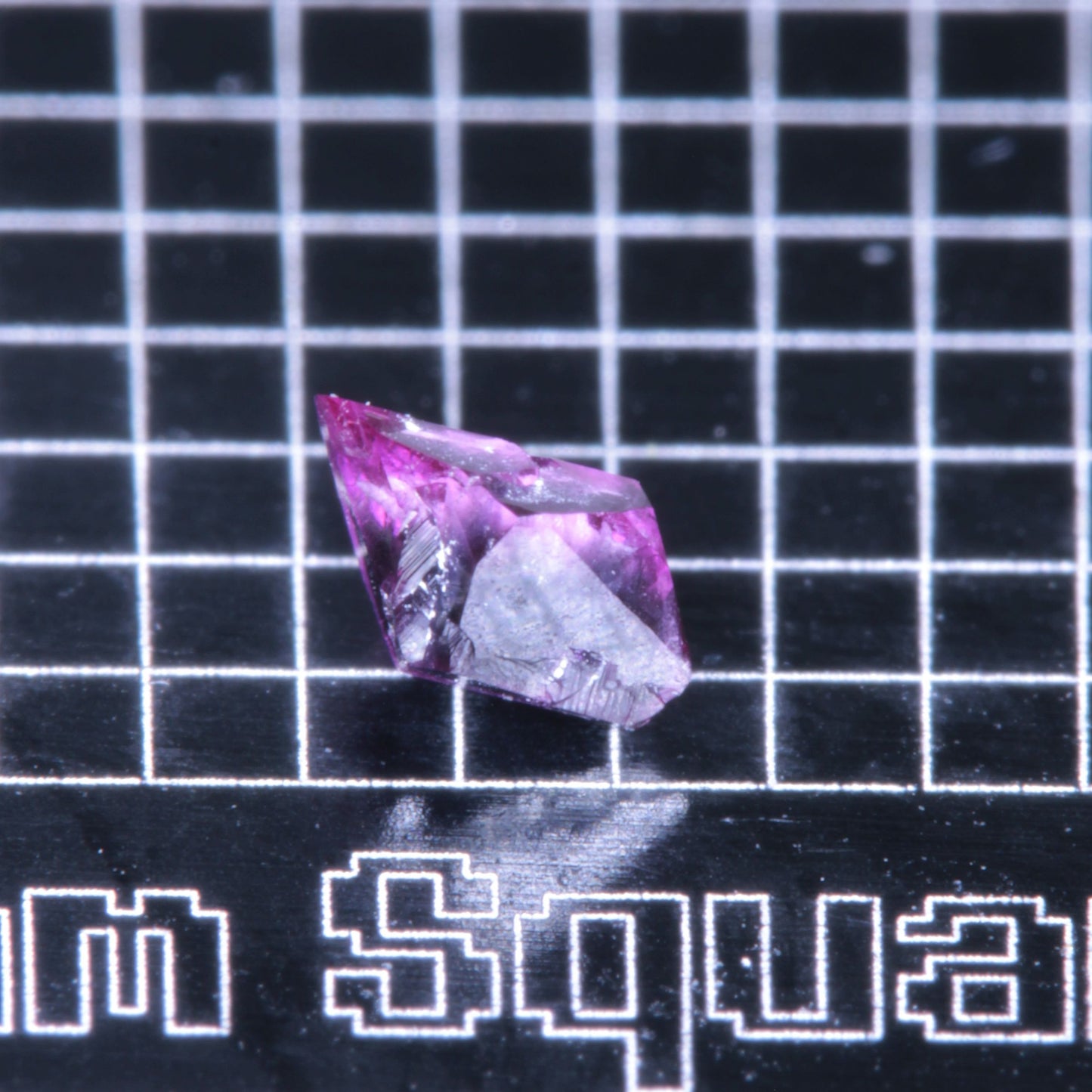 A synthetic ruby crystal on a black grid background