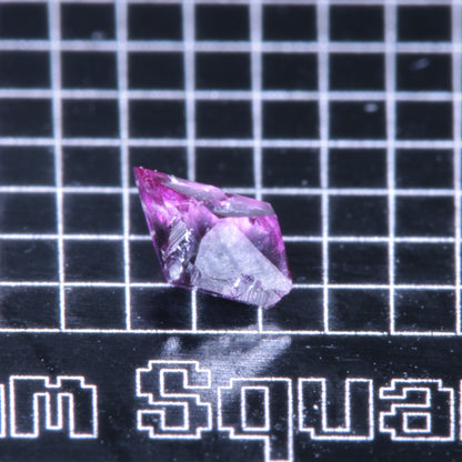 A synthetic ruby crystal on a black grid background