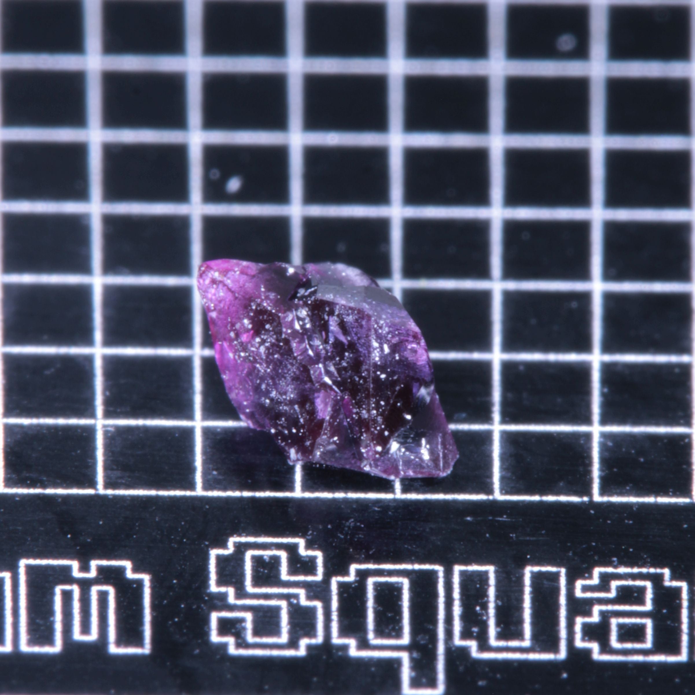 A synthetic ruby crystal on a black grid background