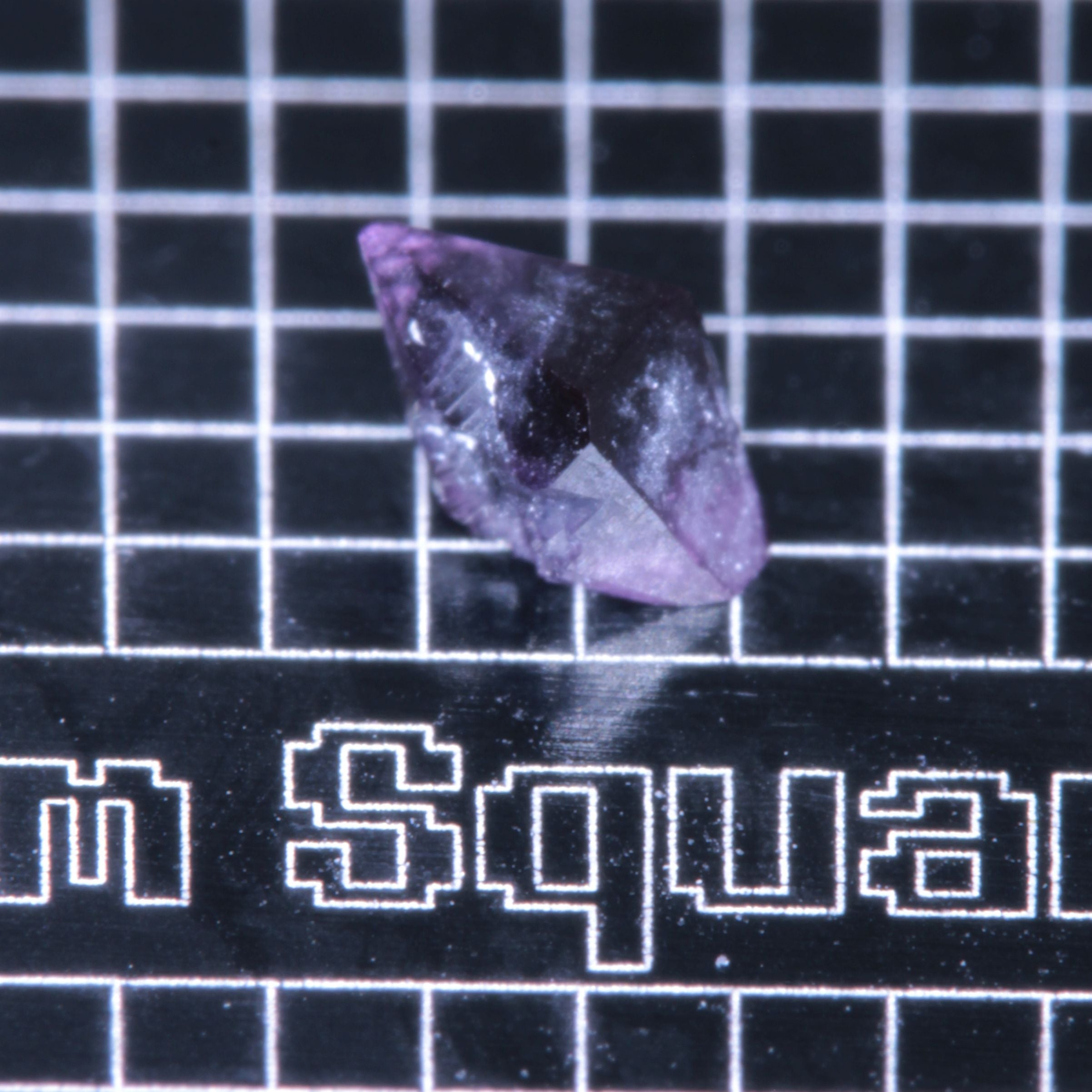 A synthetic ruby crystal on a black grid background
