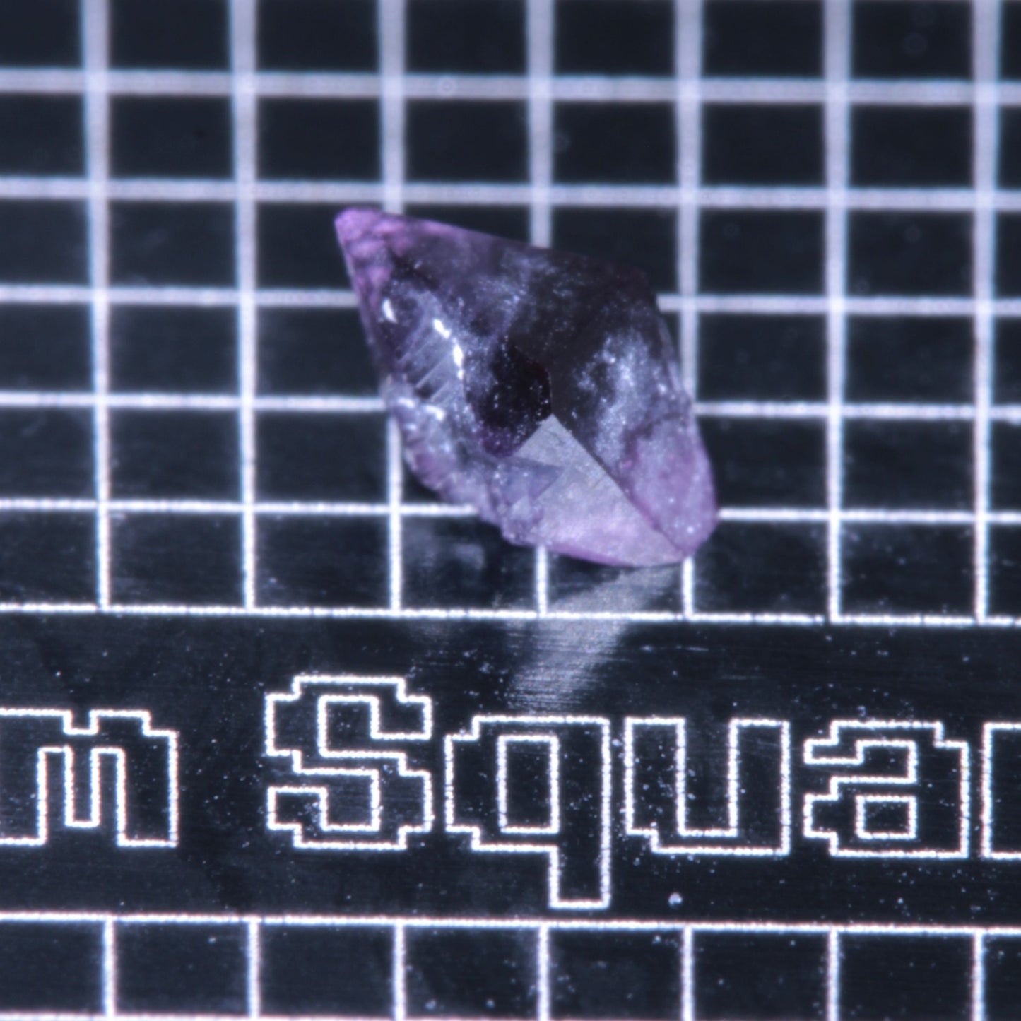 A synthetic ruby crystal on a black grid background
