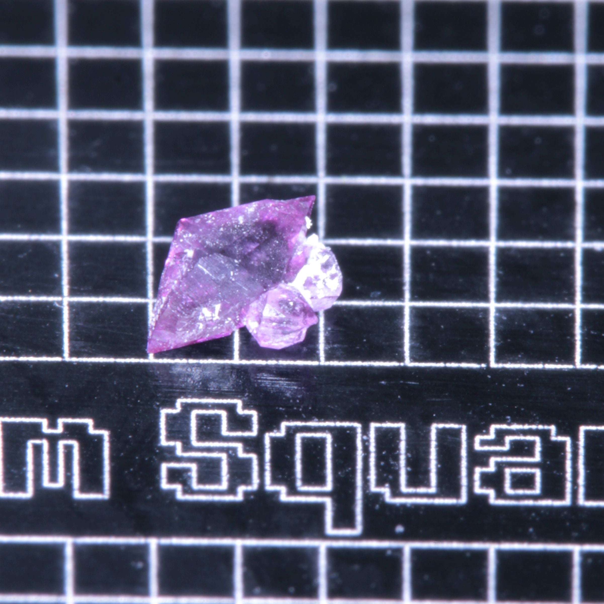 A synthetic ruby crystal on a black grid background