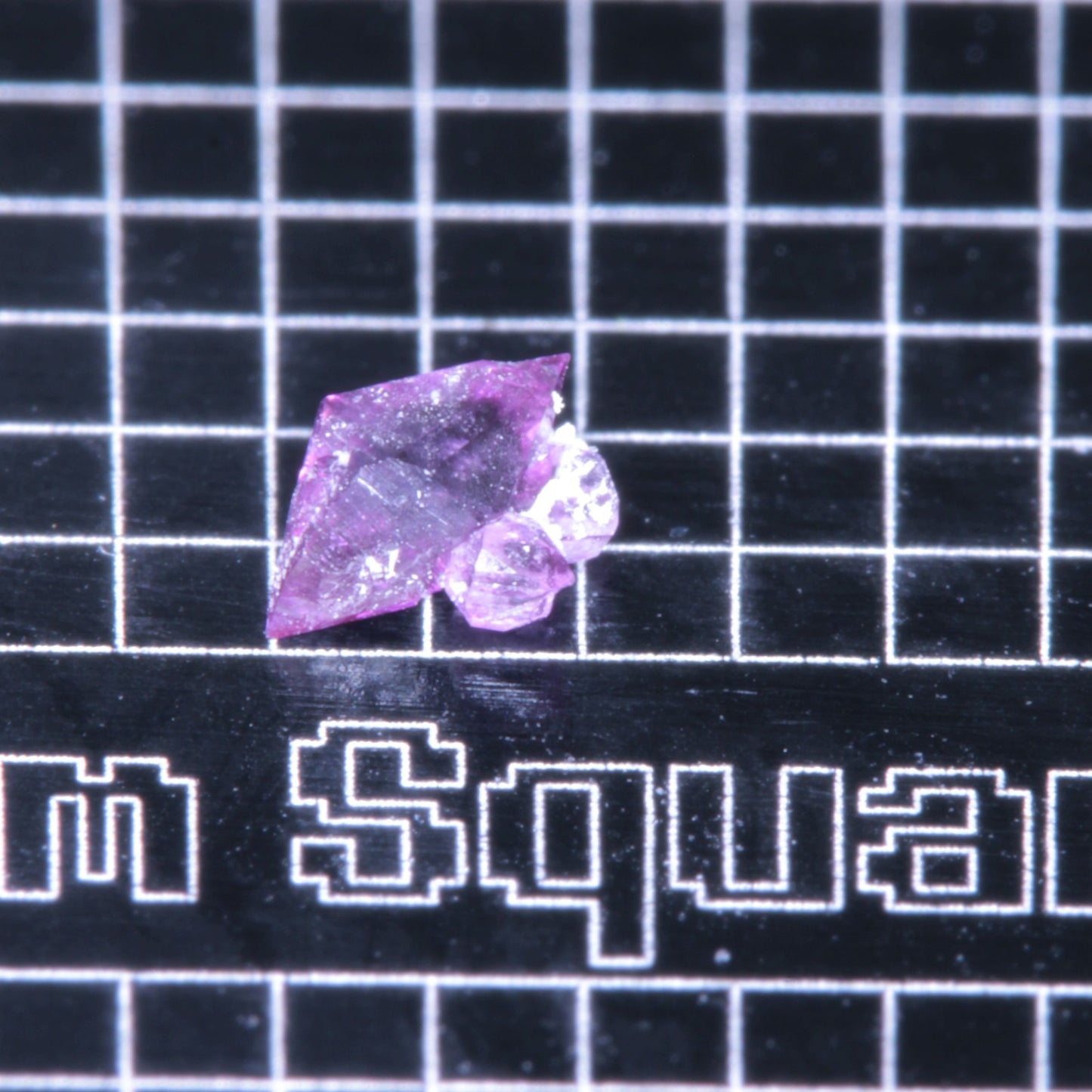 A synthetic ruby crystal on a black grid background