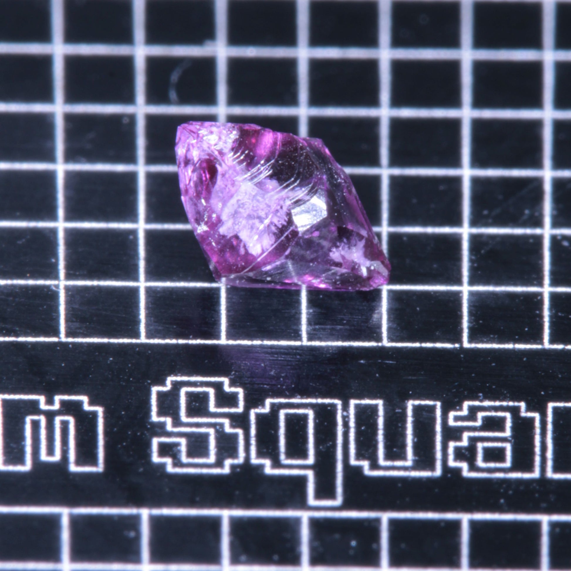A synthetic ruby crystal on a black grid background