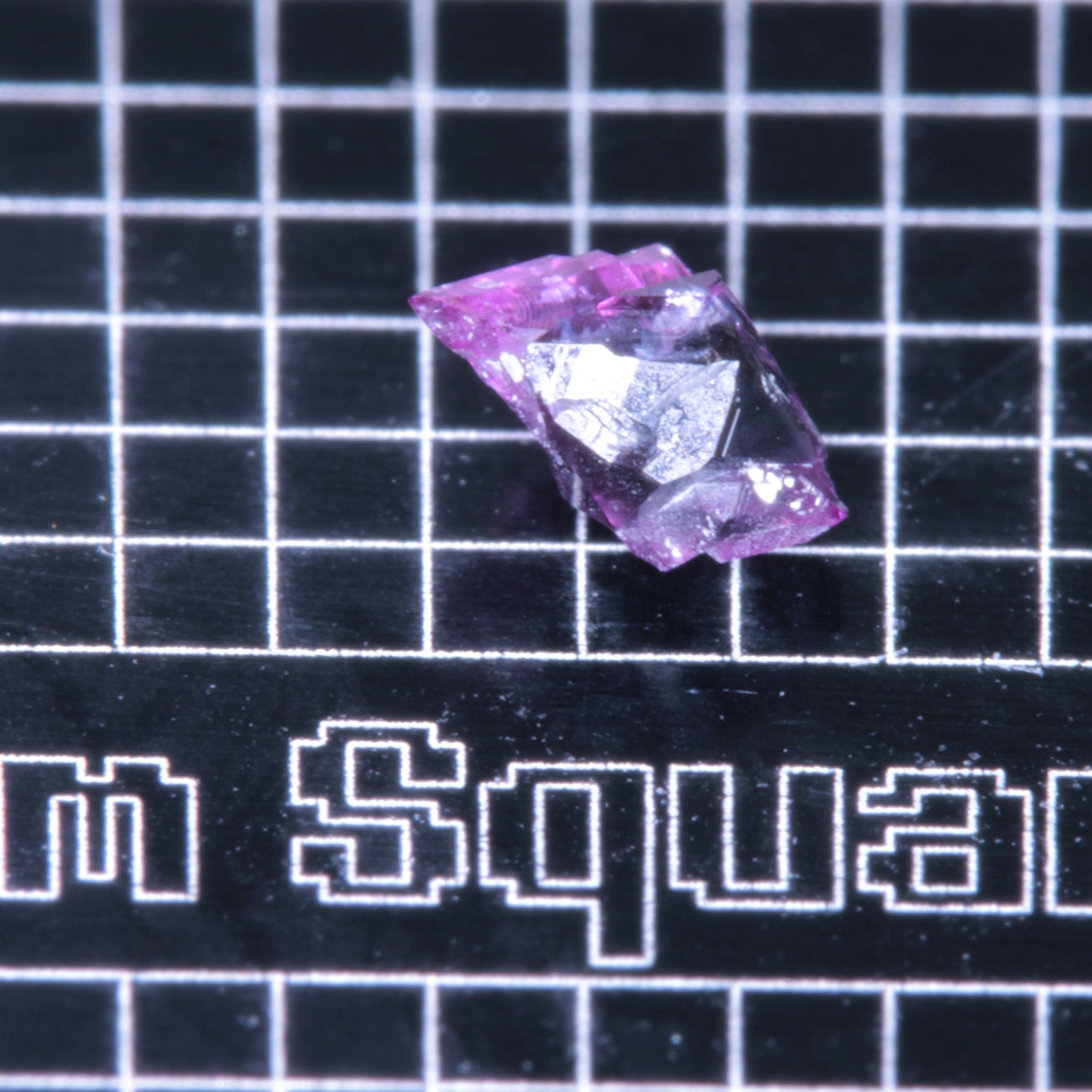 A synthetic ruby crystal on a black grid background