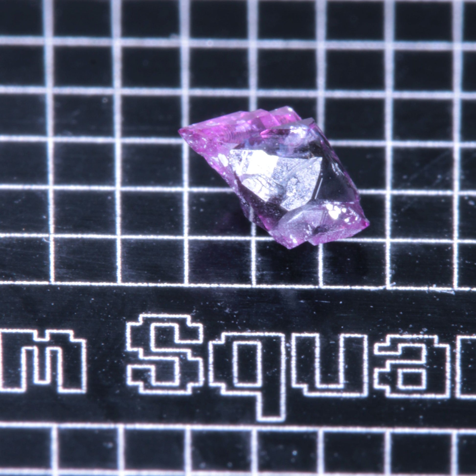 A synthetic ruby crystal on a black grid background