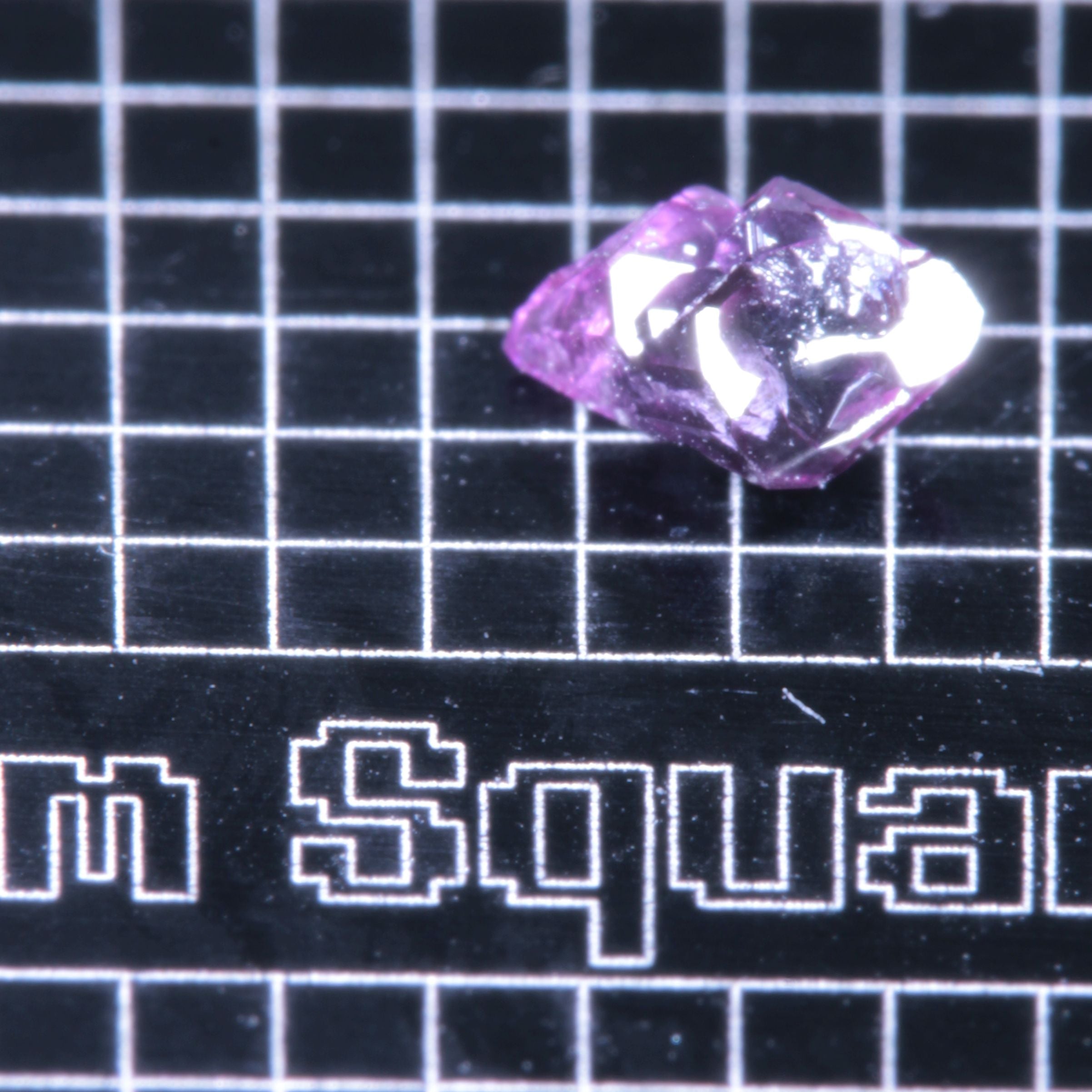 A synthetic ruby crystal on a black grid background