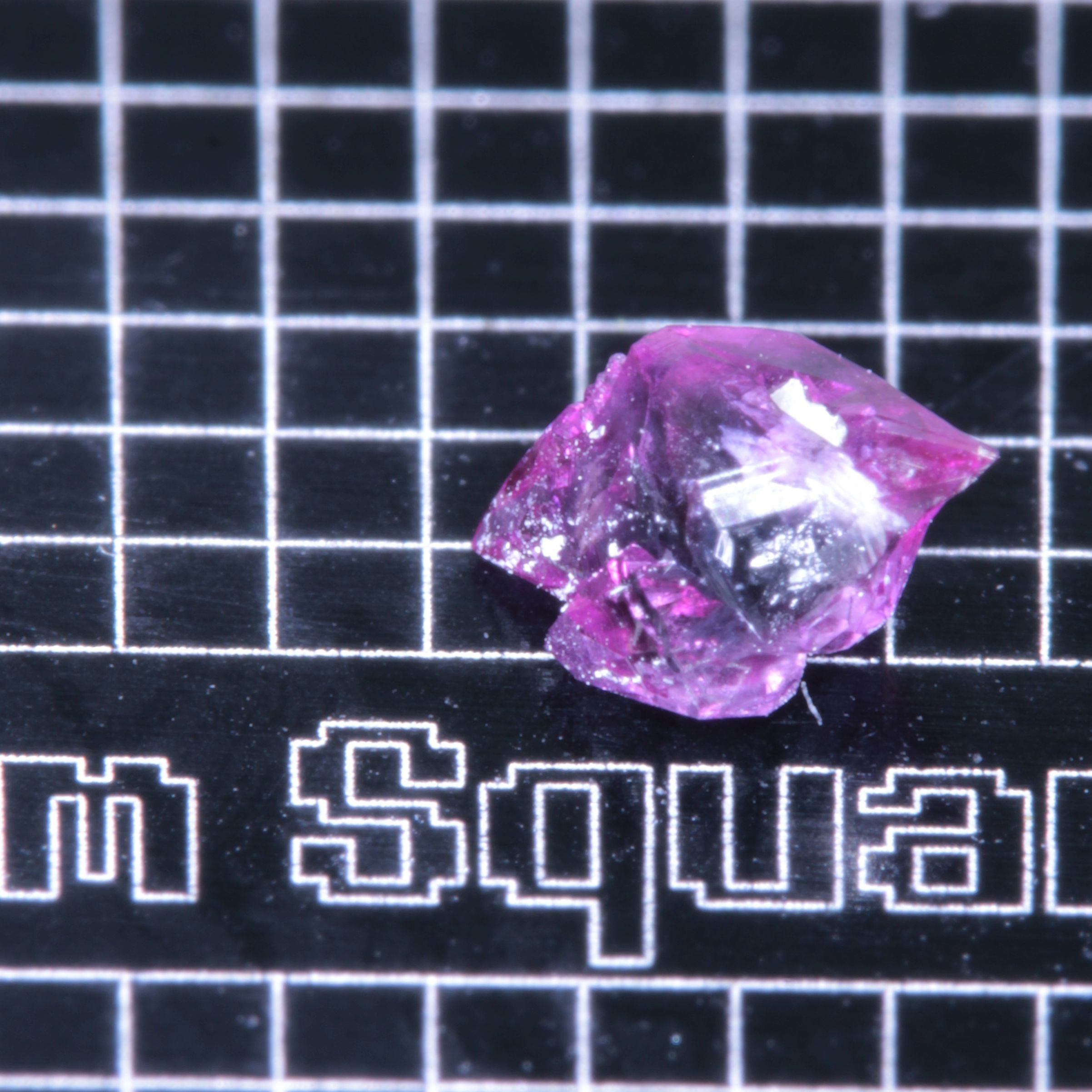 A synthetic ruby crystal on a black grid background